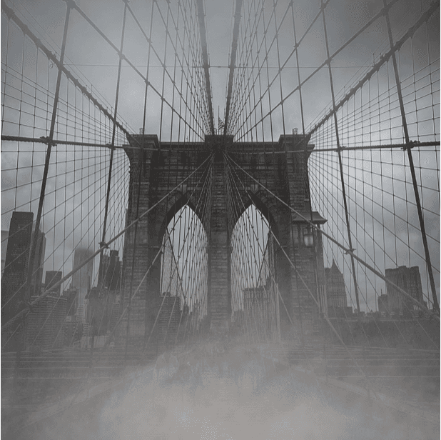 A view fo the Brooklyn Bridge on a cloudy day with mist in the distance. 