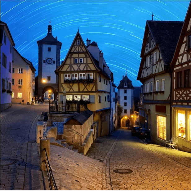 A classic old town setting with large historical buildings lit up at dusk.