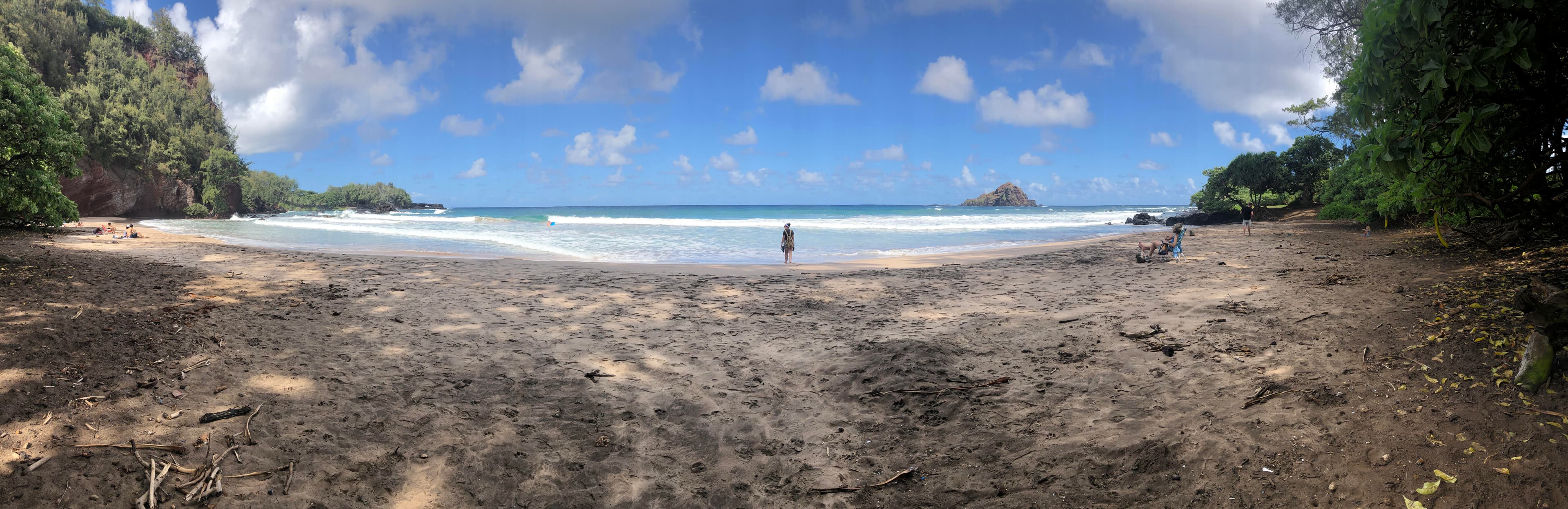 Advisor posing near the shore on a rocky beach with blue skies overheard. 