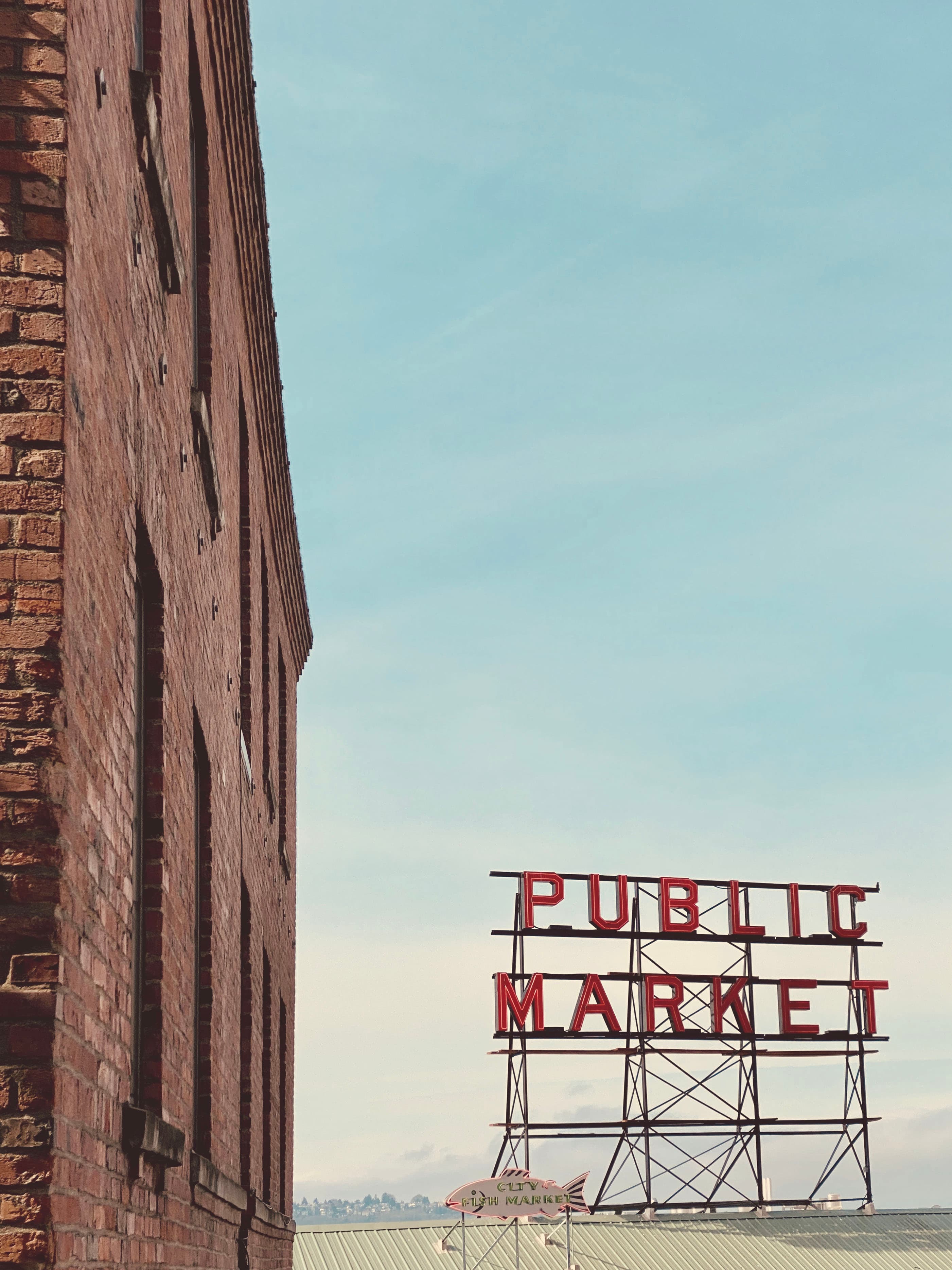 View of the Public Market sign in Seattle next to a brick building on a clear day