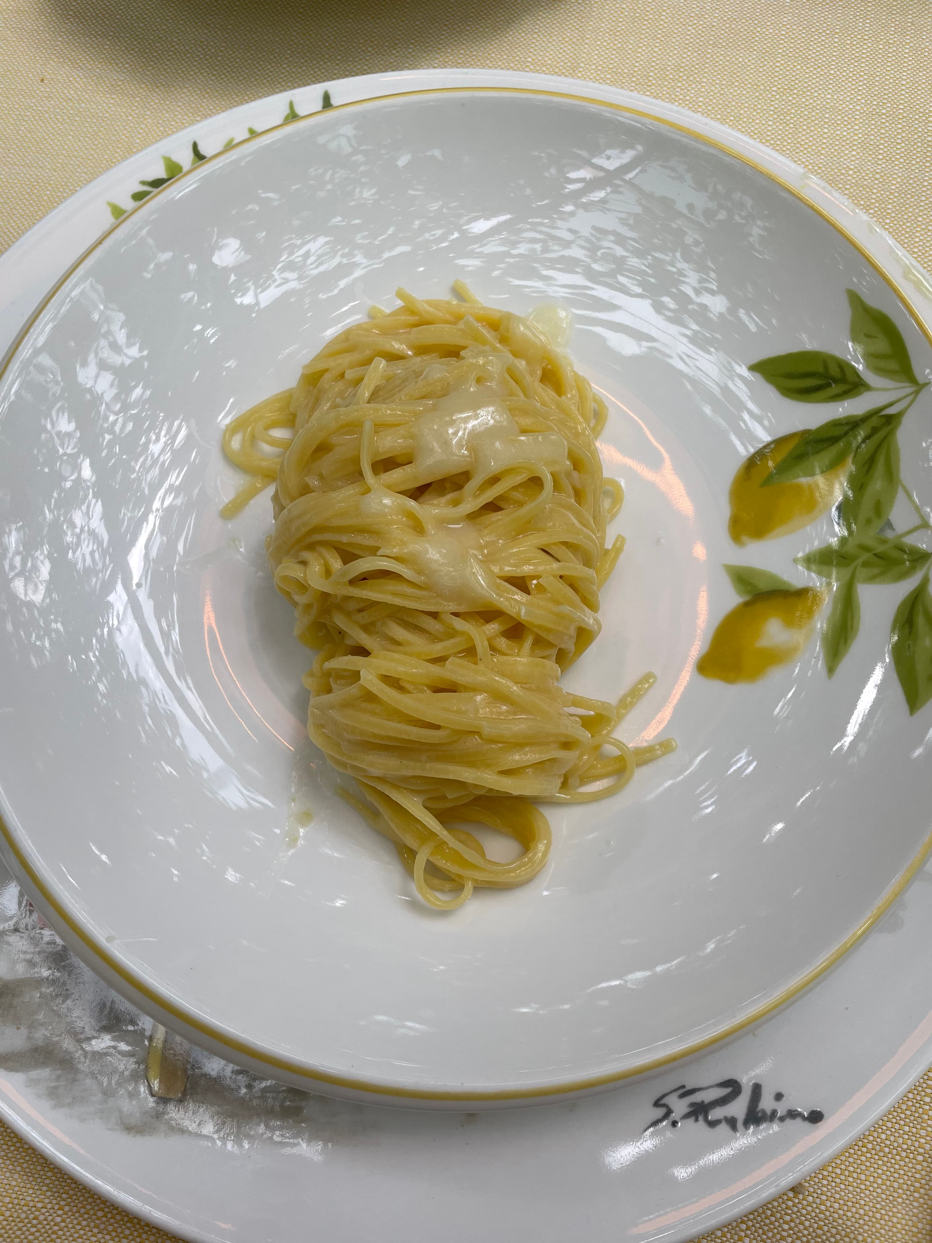 Image of a pasta dish on a white plate with the pattern of green leaves