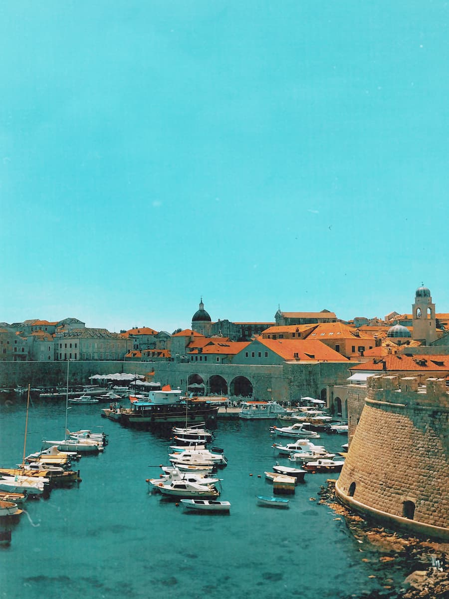 A port with lines of boats and buildings in the background.