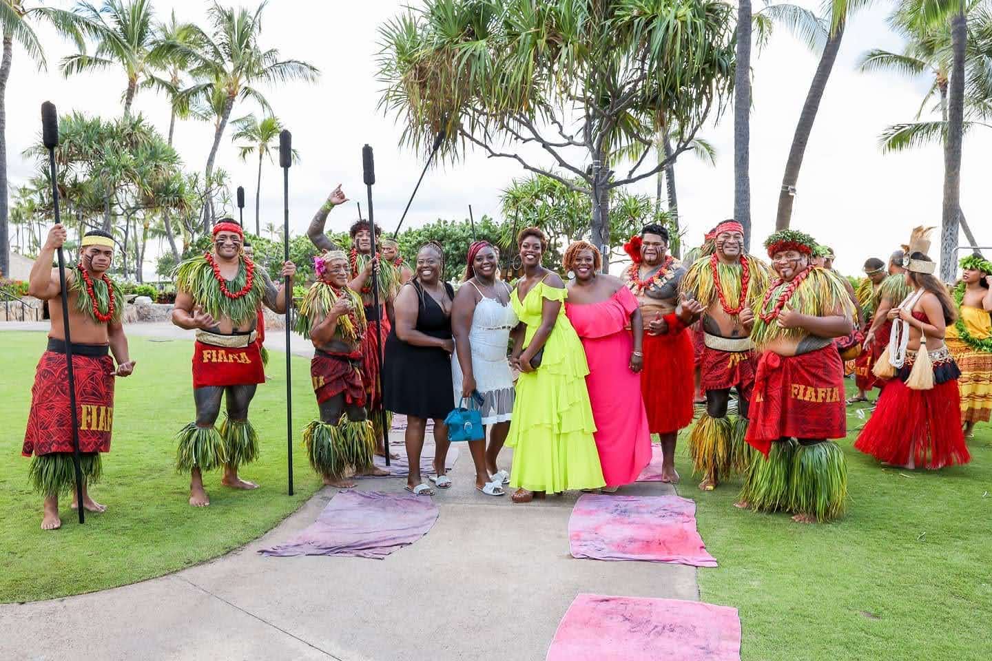 A group of people standing together at a Luau in Ohau, Hawai'i, surrounded by people in traditional garb during the day.