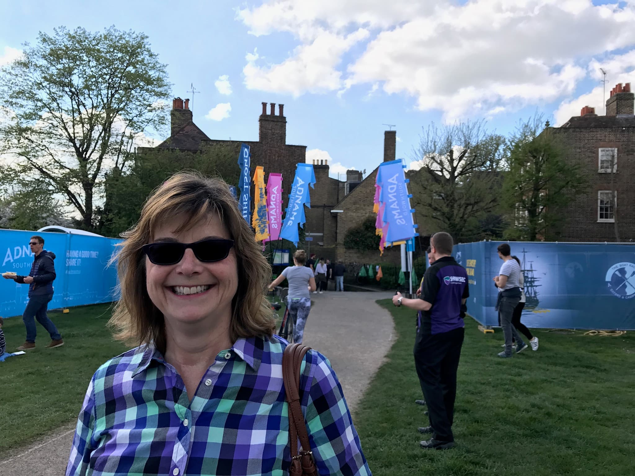 Photo of advisor in a plaid shirt and glasses posing in front of a building during the daytime.