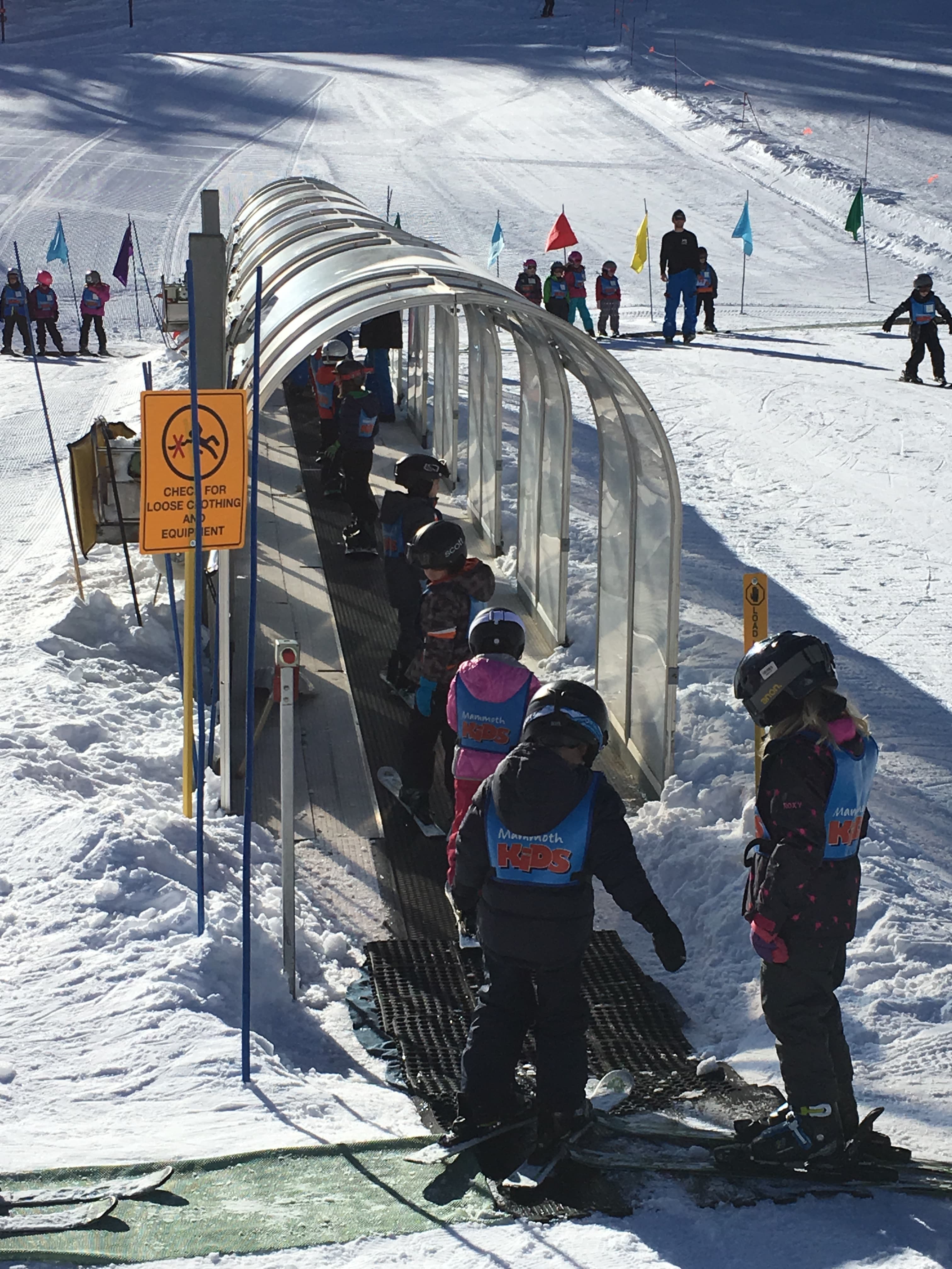 View of several people in ski gear going through a clear plastic tunnel on a snowy landscape