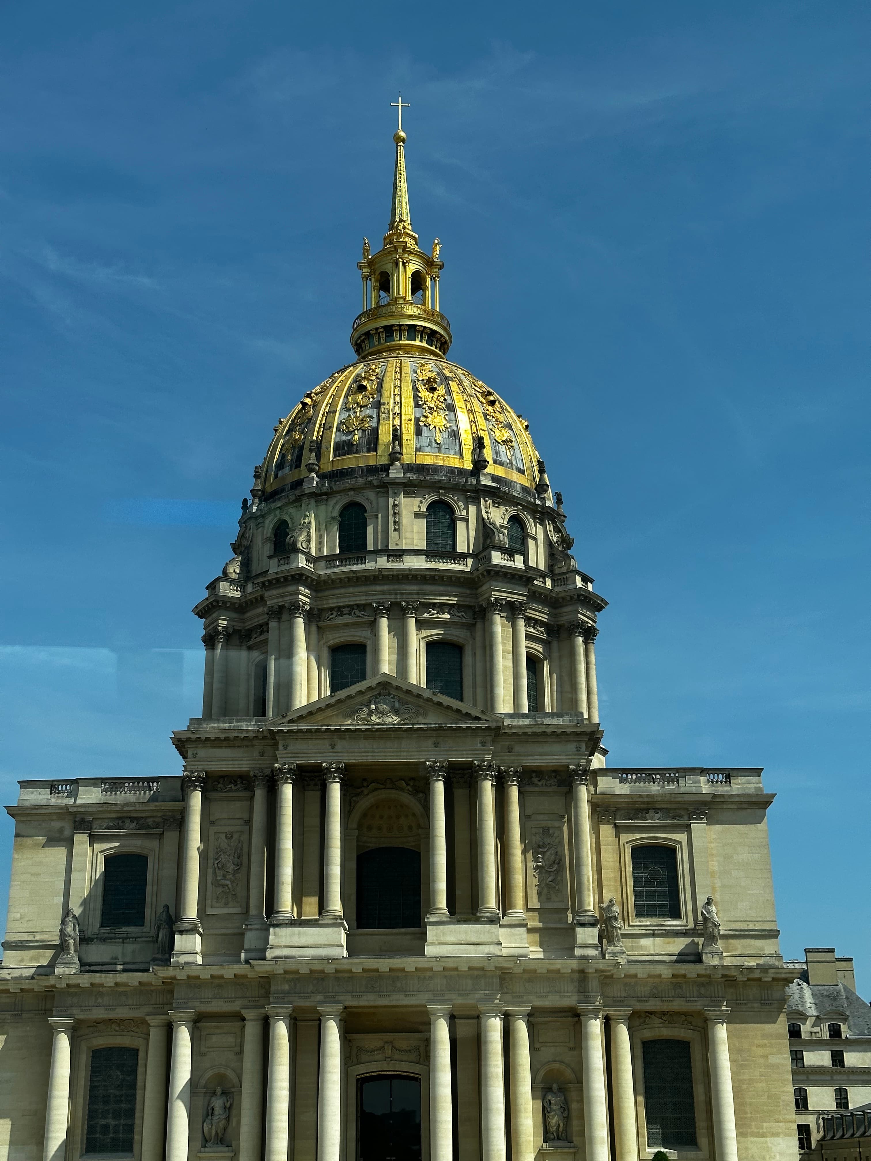 View of a domed building with columns and a spire on top on a clear day