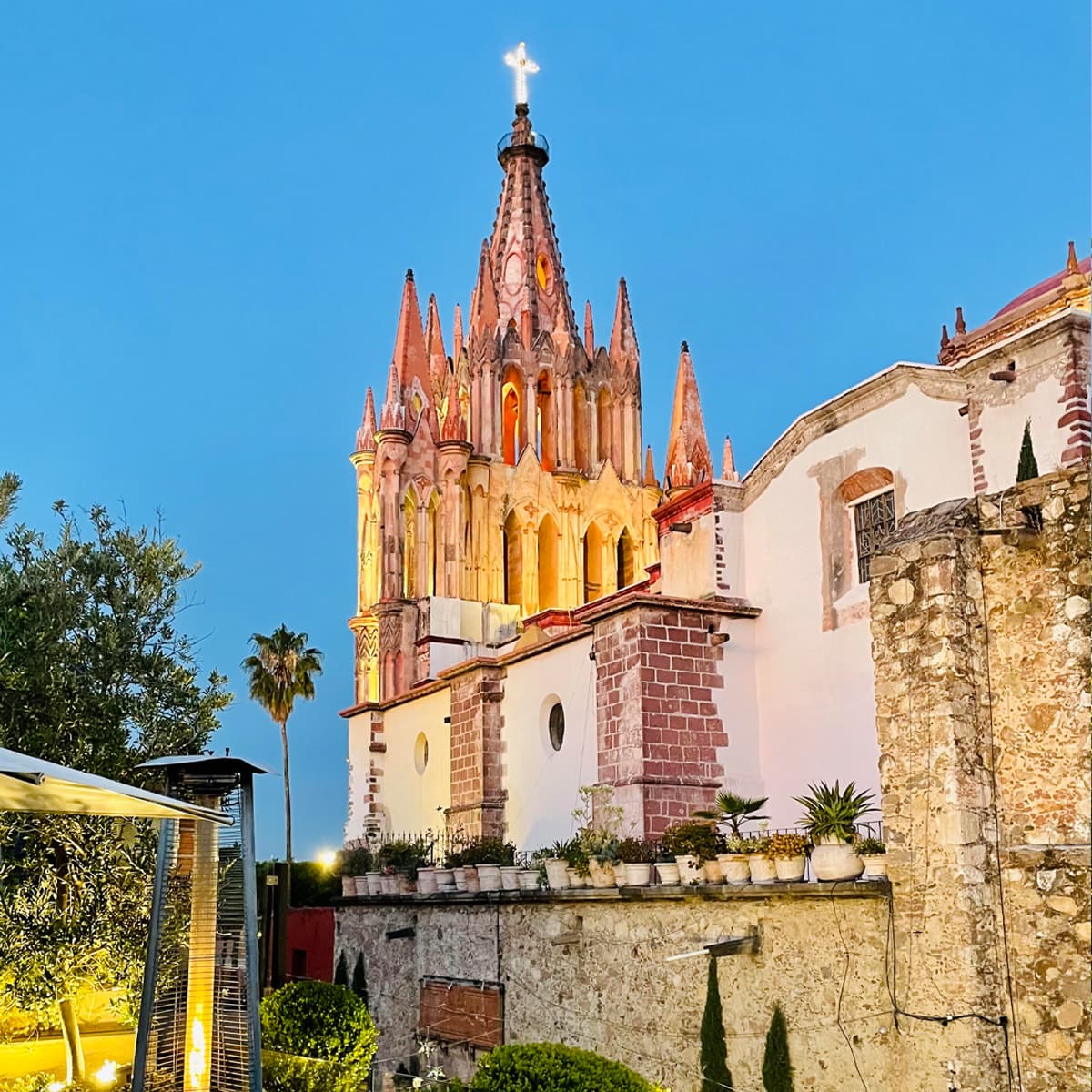 View of the light pink cathedral in San Miguel de Allende and other buildings under blue skies