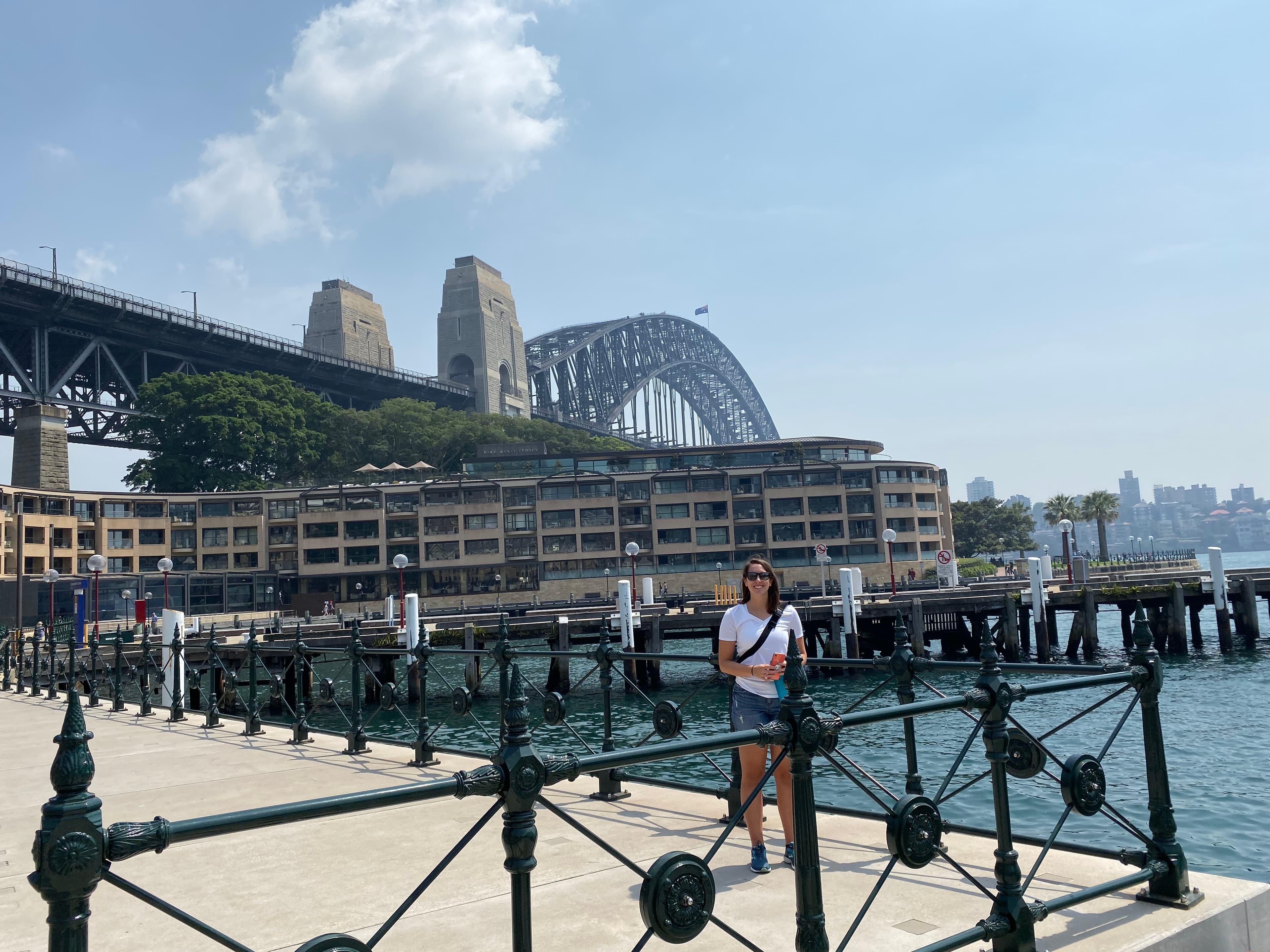Advisor stands next to a railing near water with a bridge in the background.