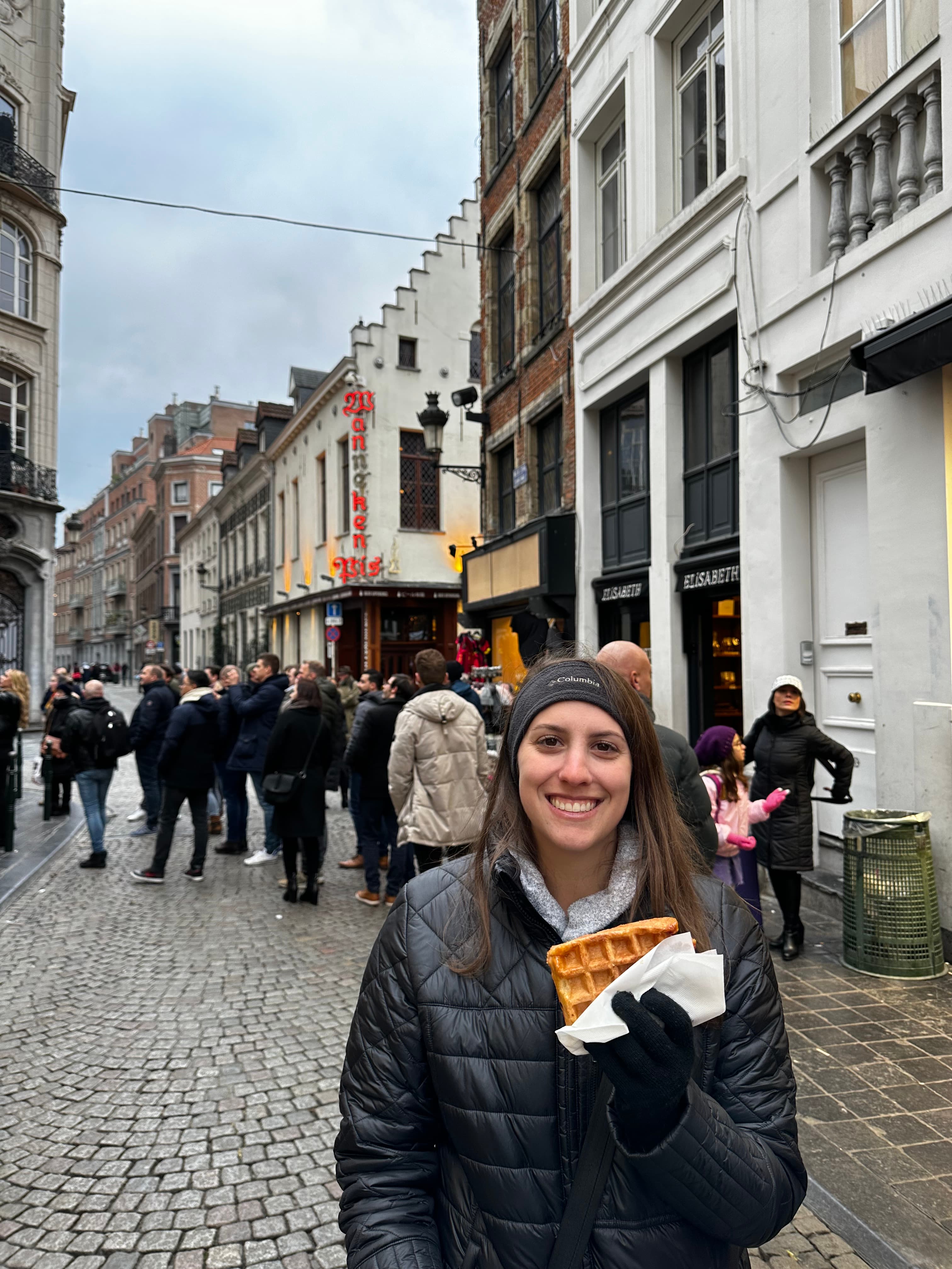 Advisor standing on a cobblestone street holding a waffle.