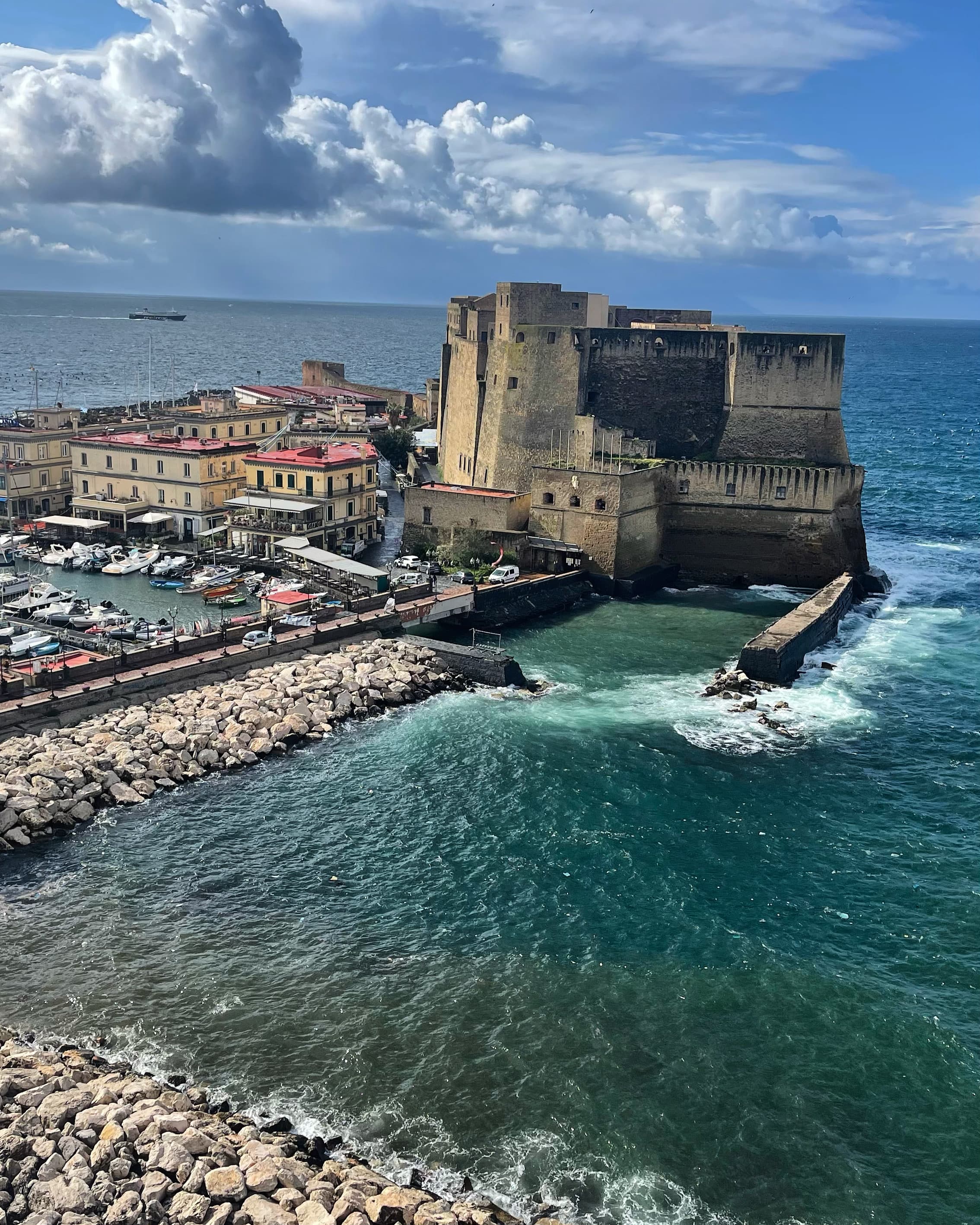 Beautiful view of an old castle on the sea next to a marina on a sunny day