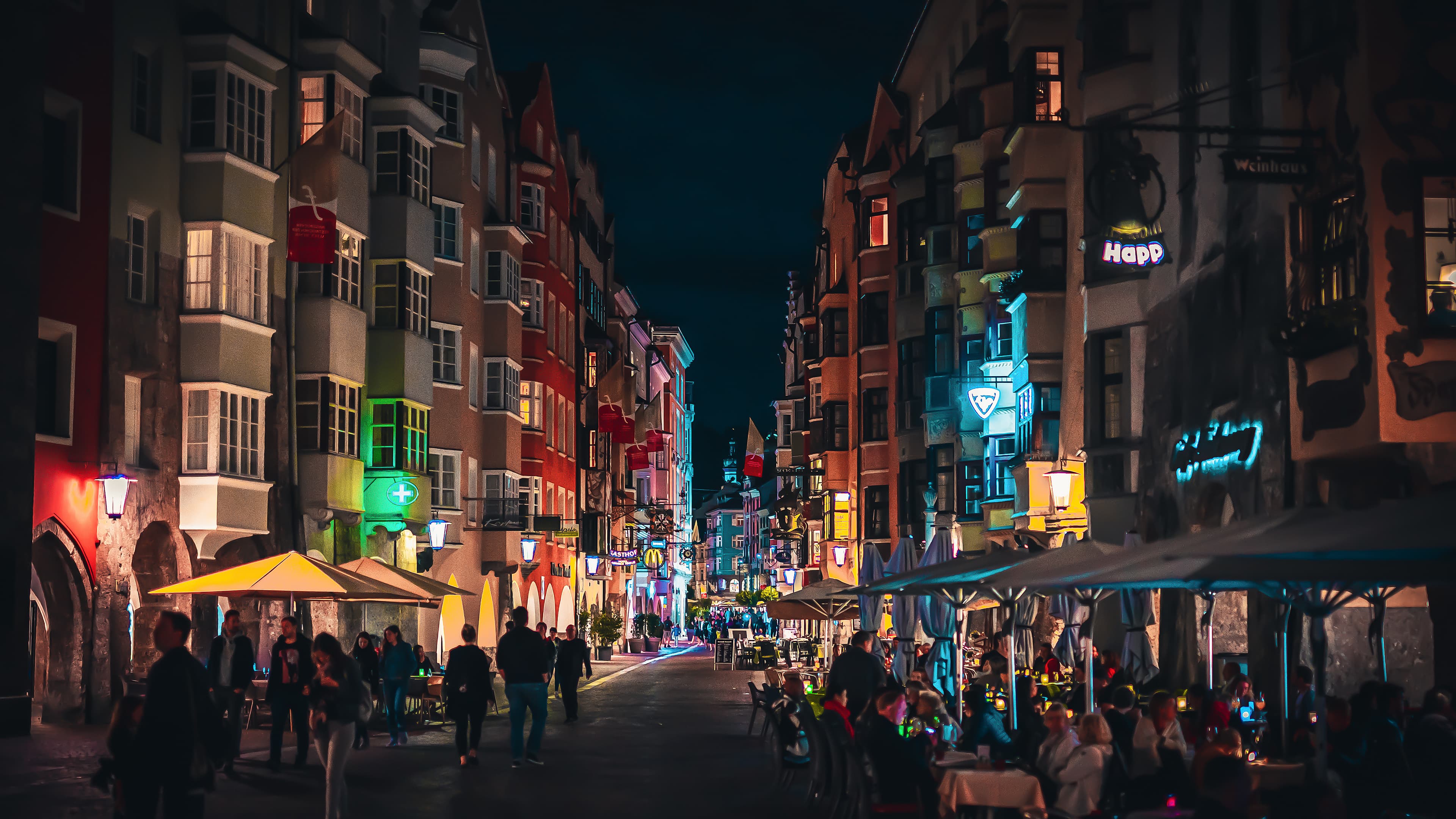 Quaint downtown buildings dotted with neon signs under a clear nighttime sky. 