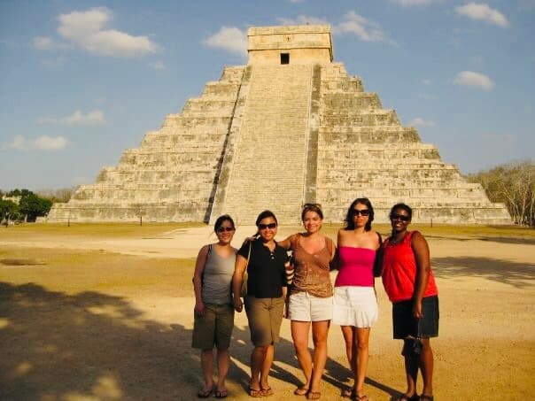 A group of women pose in front of a stepped pyramid temple.