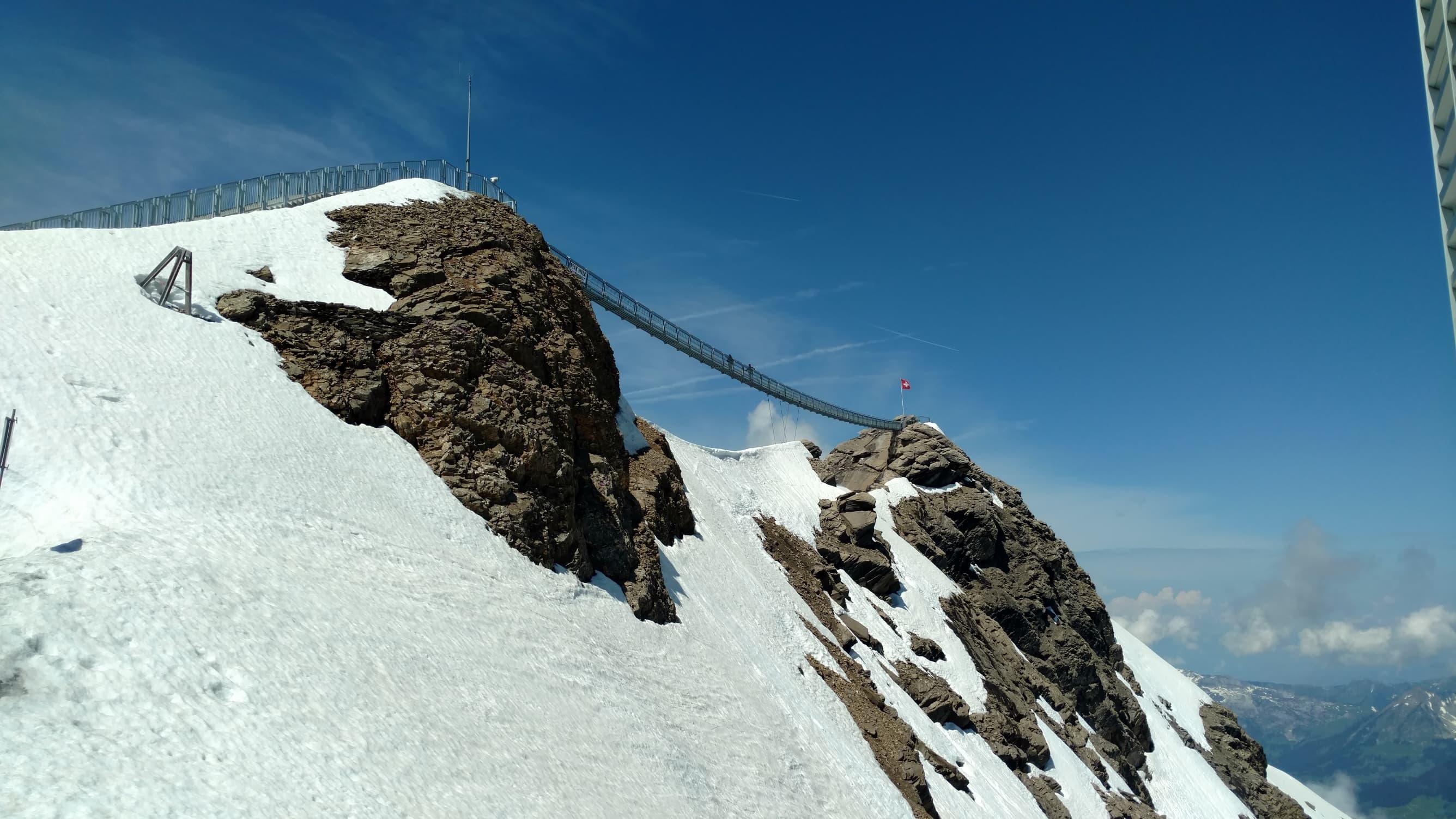 Mountains covered in snow connected by a bridge.