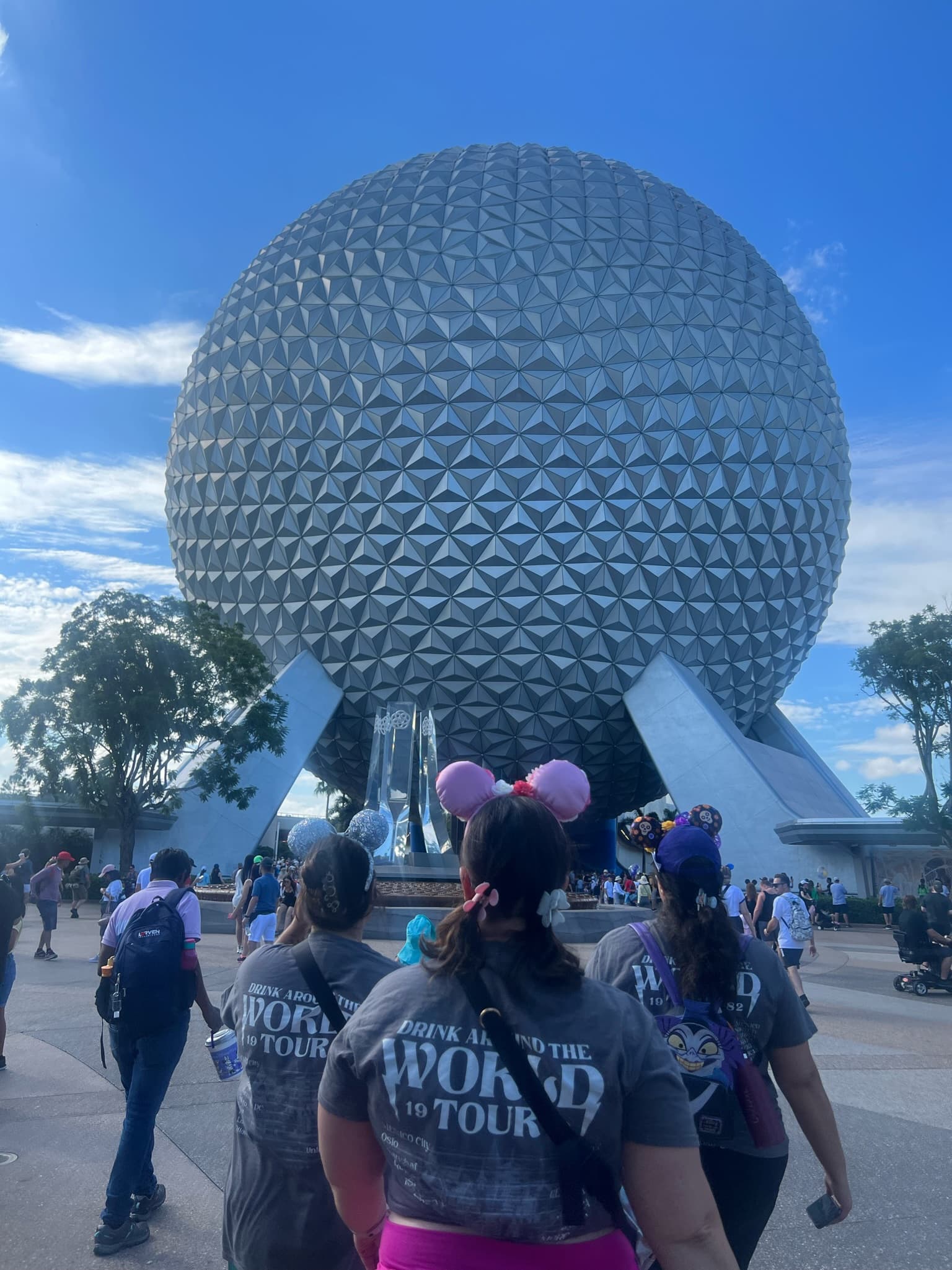 Visitors walking towards Epcot in Walt Disney World, wearing matching t-shirts and Mickey ears.