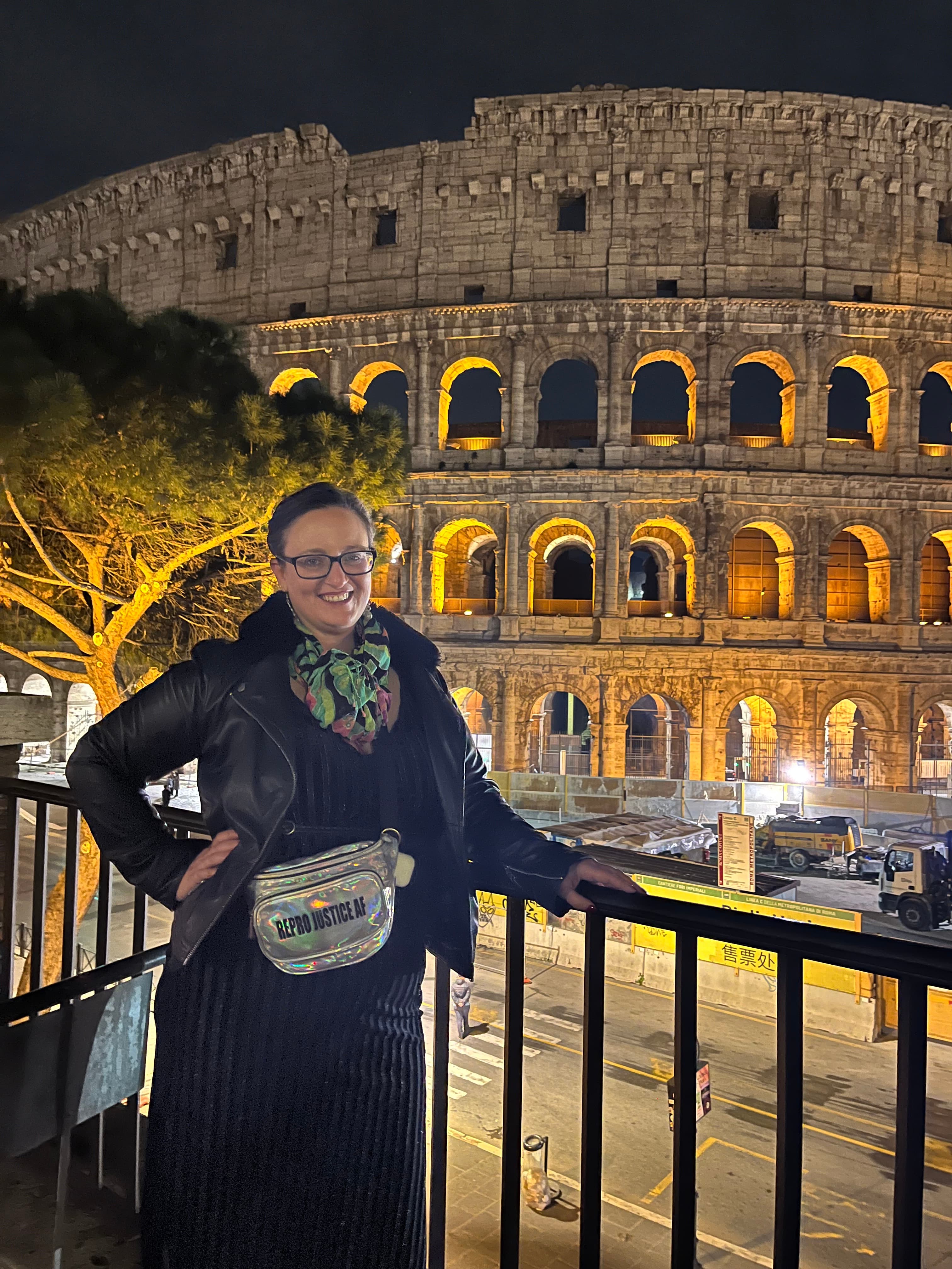 Advisor leaning against a railing overlooking a tall building at night.