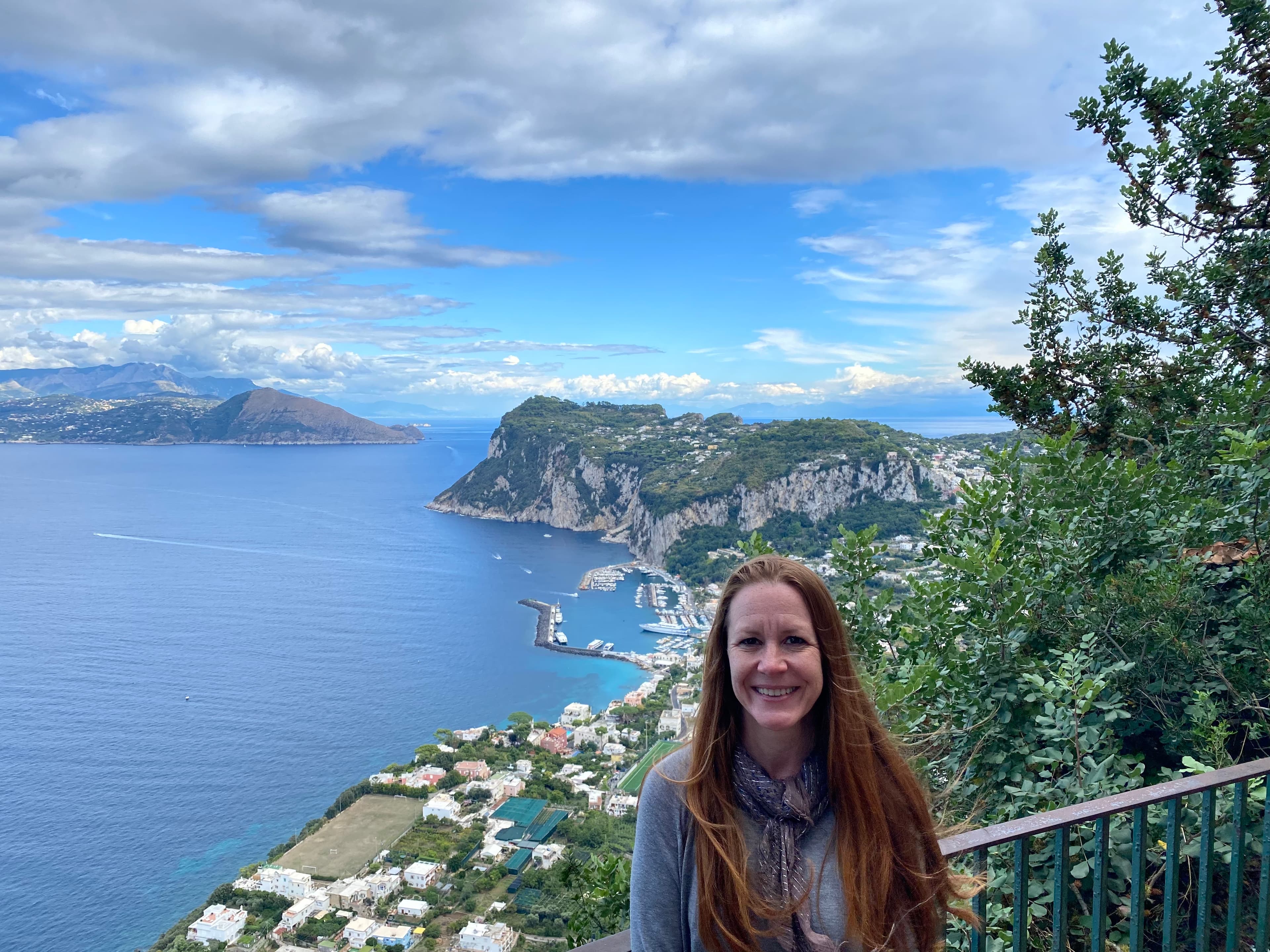Advisor posing for an image with the ocean and a seaside town in the distance.