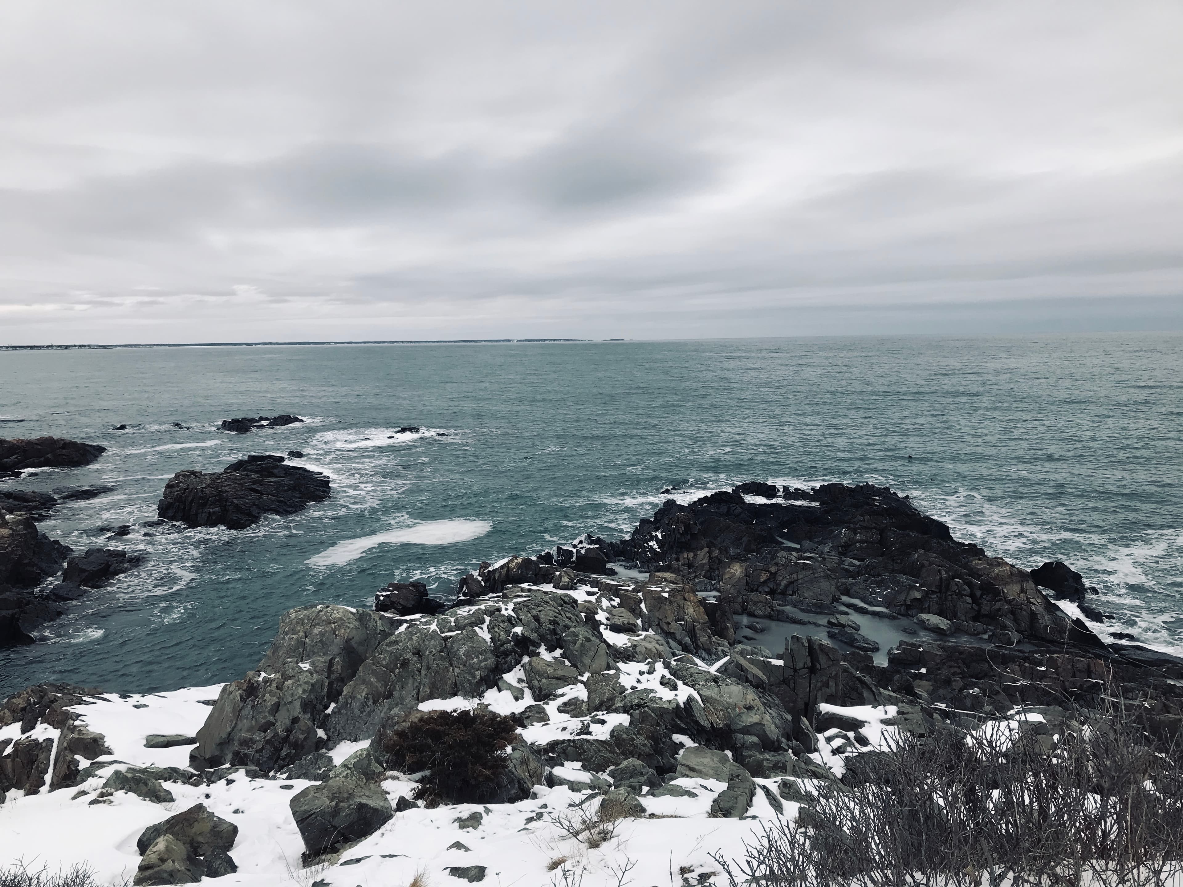 Beautiful view of a winter coastal landscape with snow-covered rocks and cloudy skies