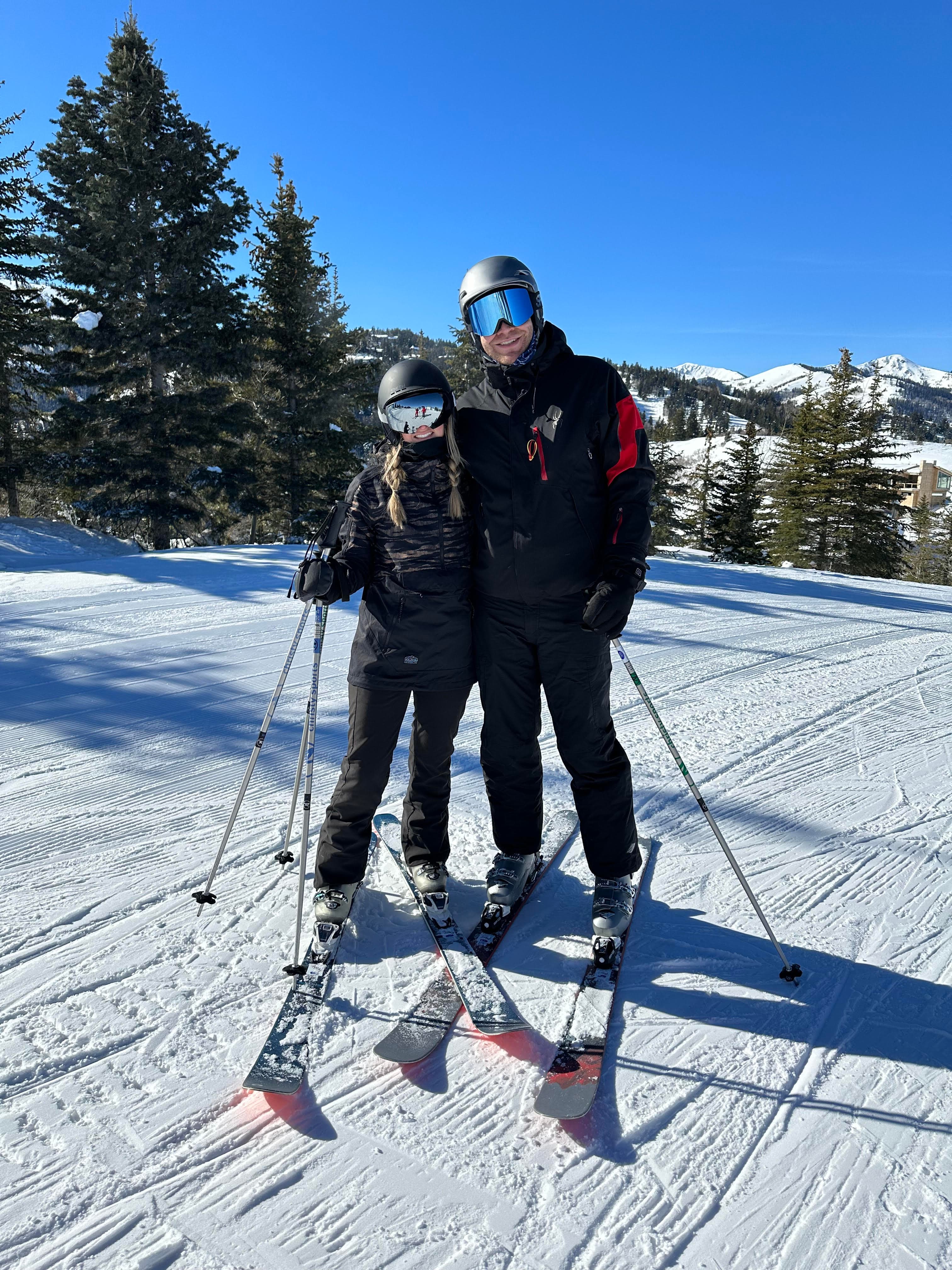 Advisor posing with another person on skis on a mountainside.