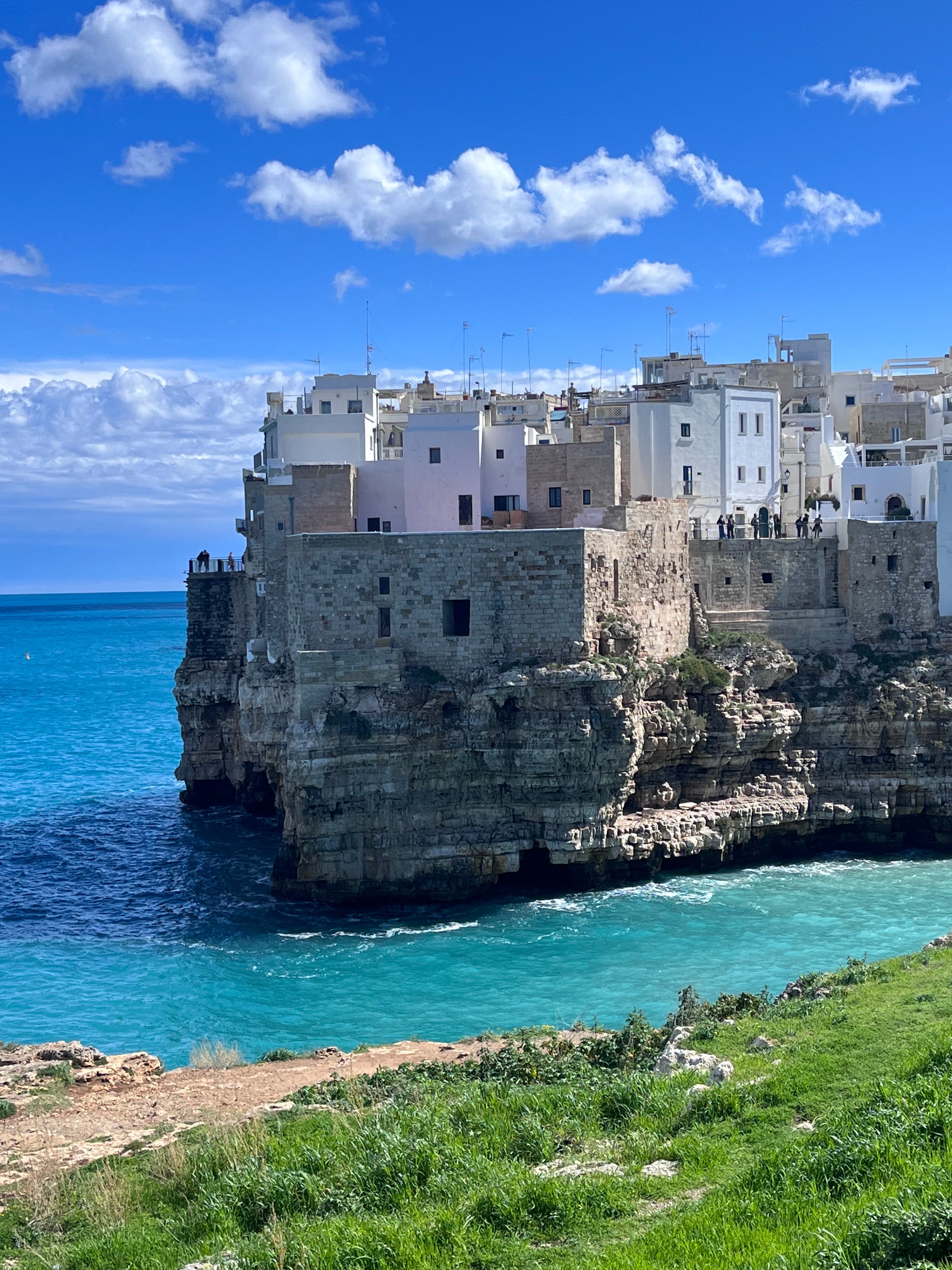 A view of an ancient city in a cliff descending into the ocean during the daytime. 