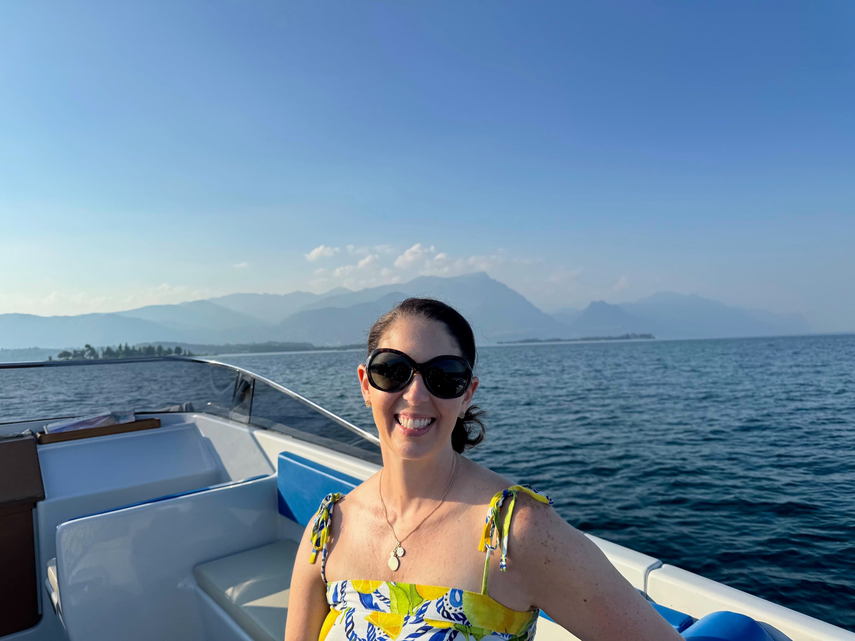 Advisor posing on the bow of a boat with the calm ocean behind her and mountains in the distance.
