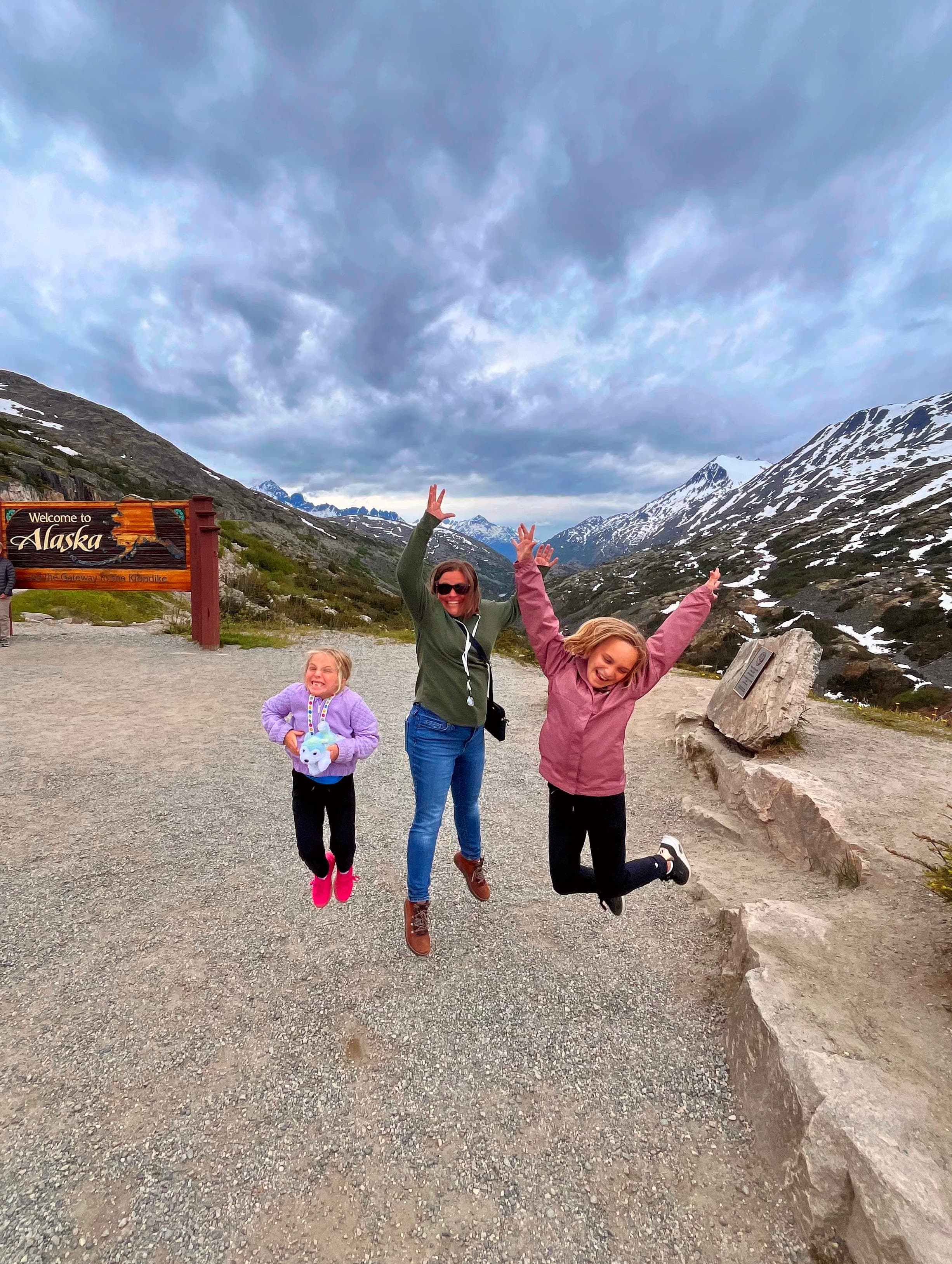 View of Mike’s family jumping in the air with a mountain landscape behind them