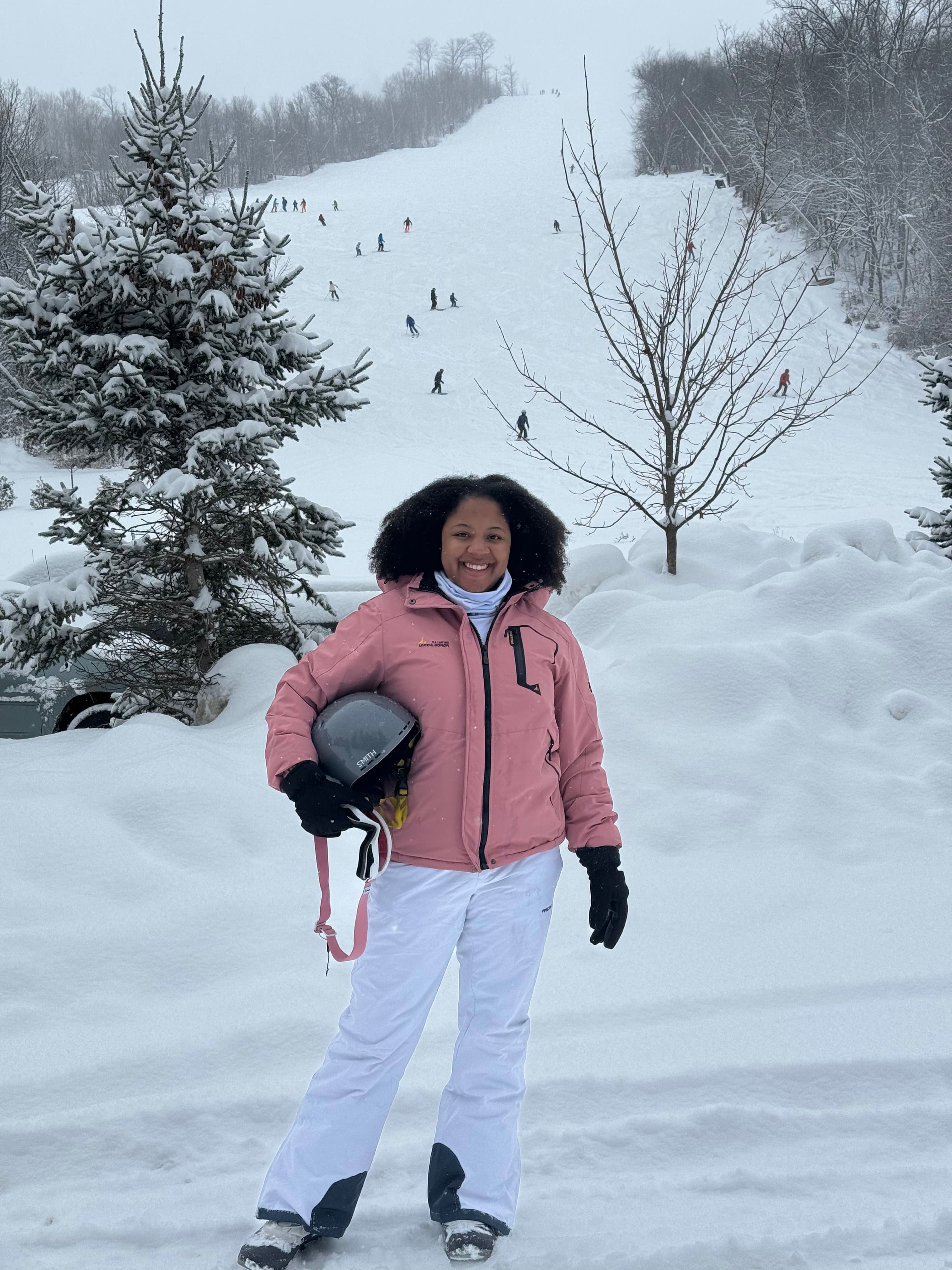 A woman in a pink jacket standing on a snow covered slope.