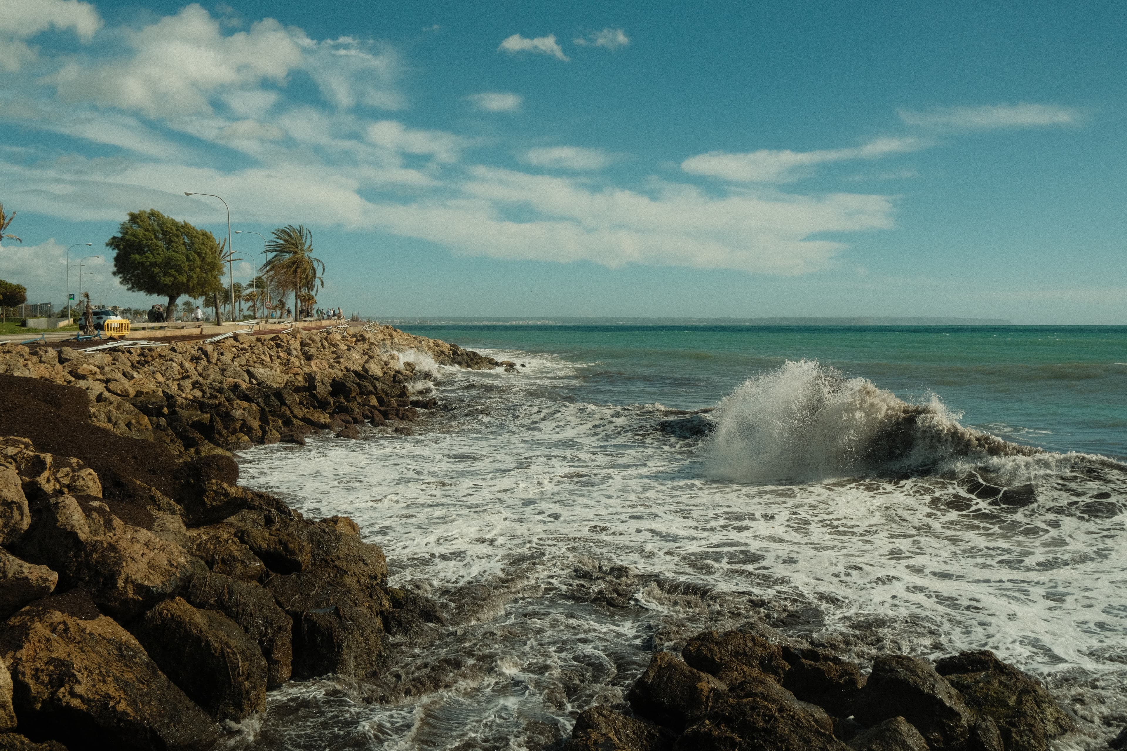  Waves crashing against rocks at beach, creating white foam and mist in the air.