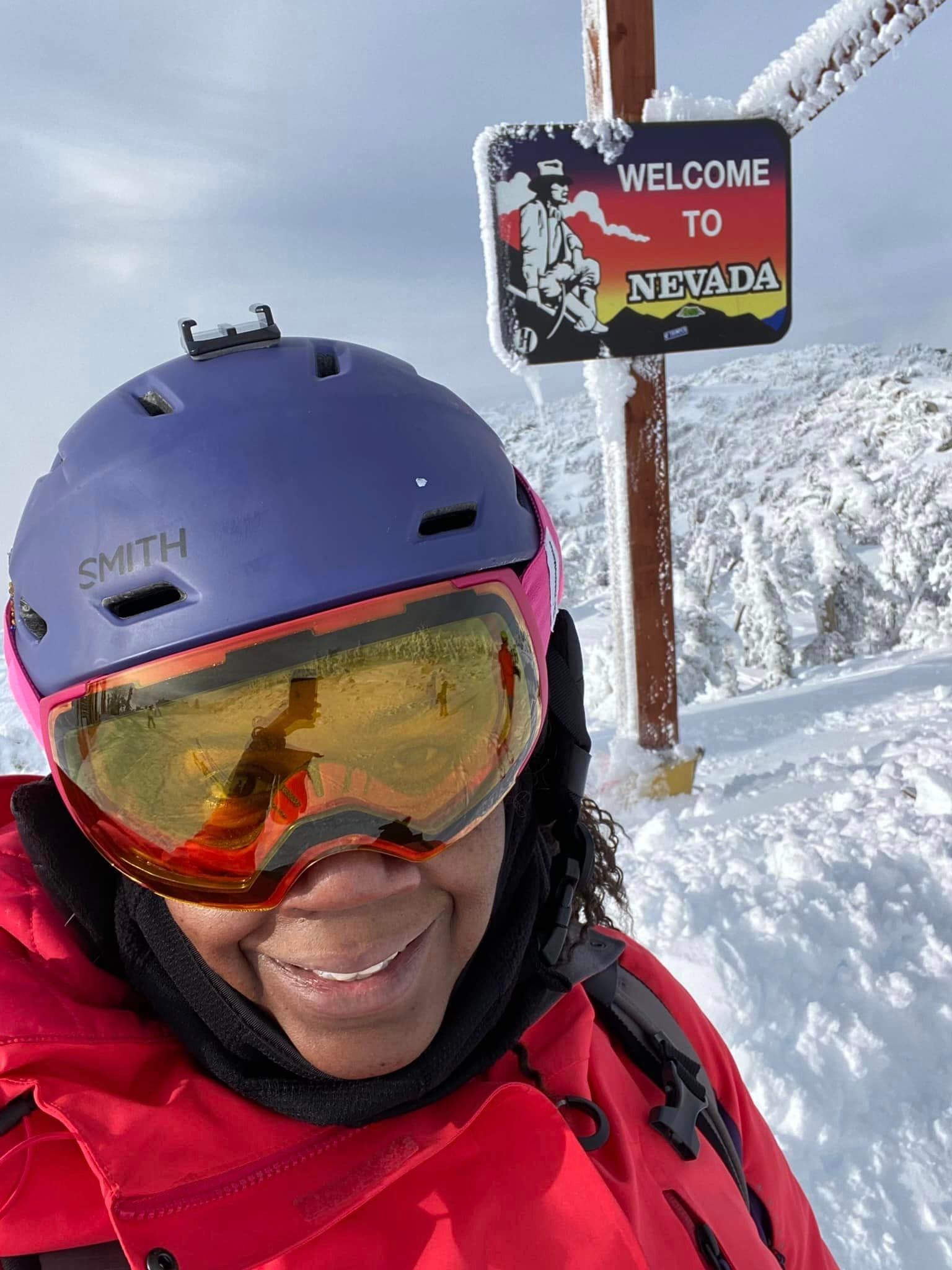  Female skier in red jacket and goggles on snowy mountain slope.