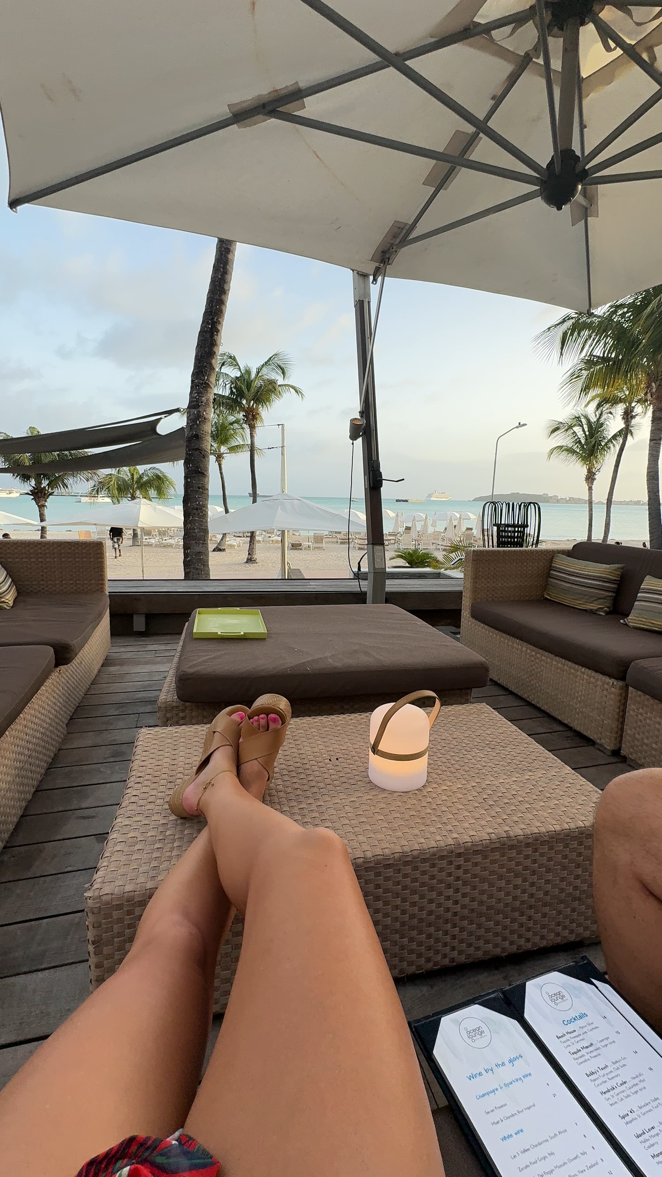 An image of the advisor sitting on a couch with a view of the ocean and a sun umbrella. 