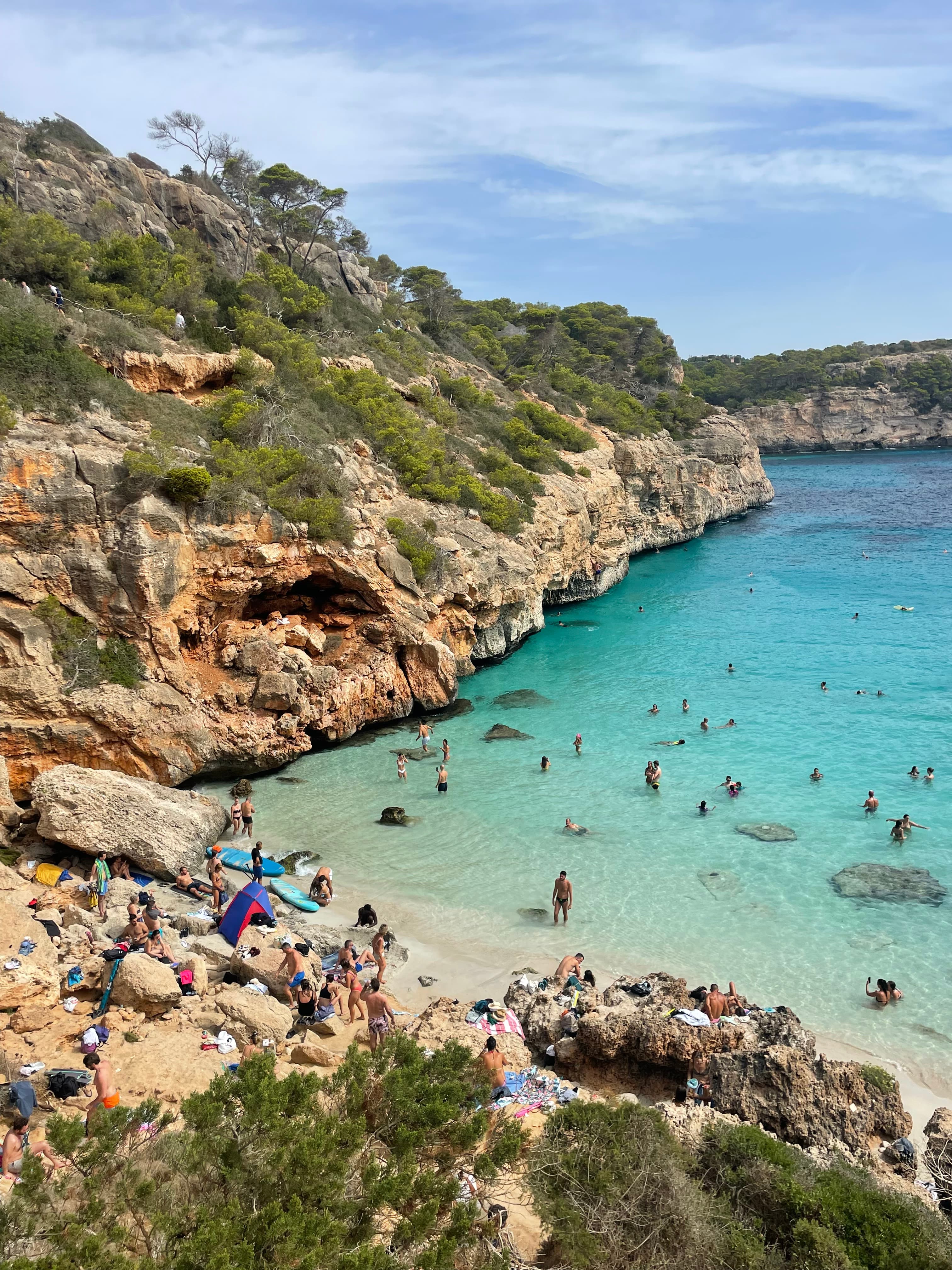 Beautiful view of a rocky coastline and small bay with several people swimming in shallow water