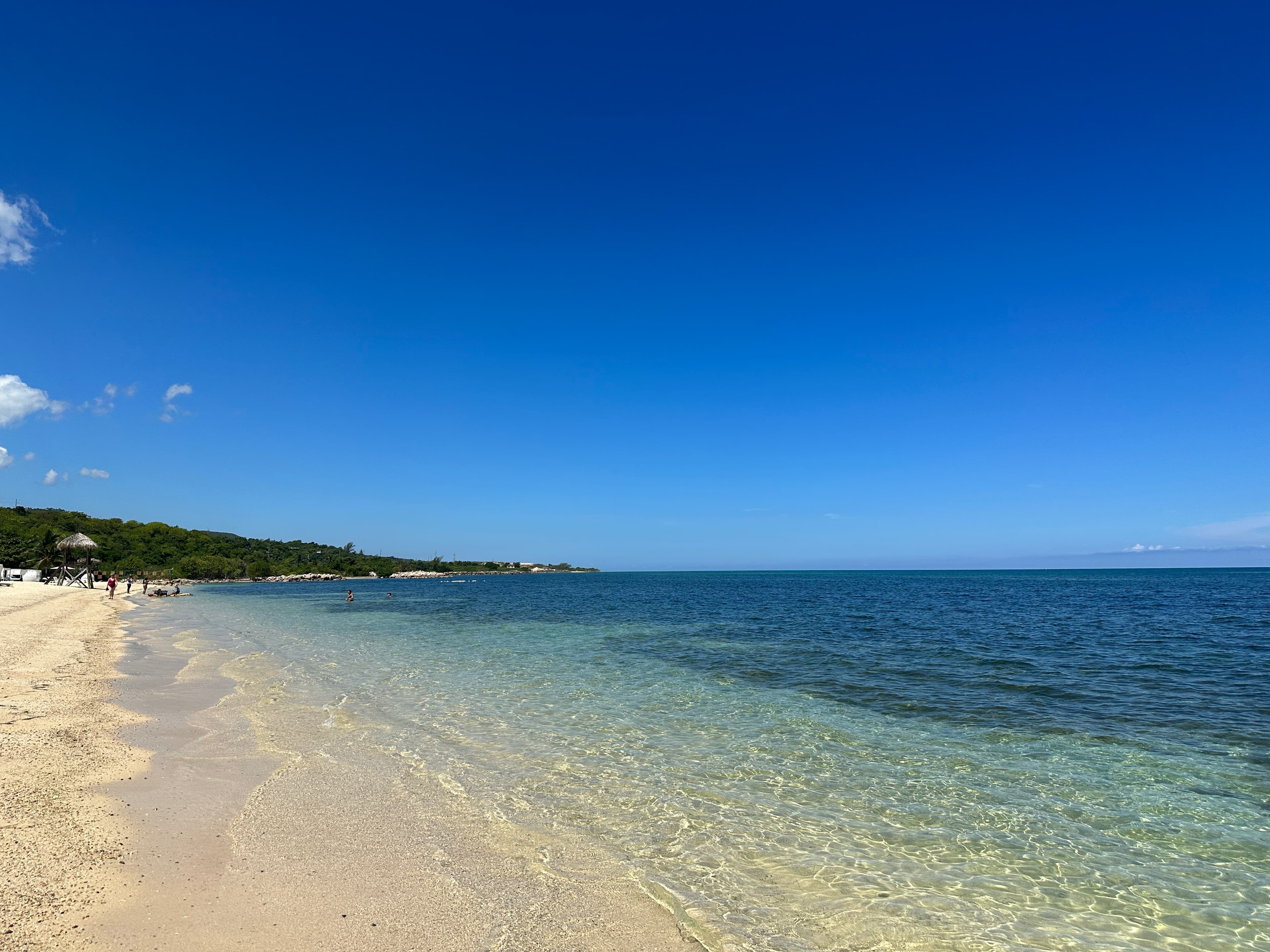 View of a long beach and calm clear ocean waters under sunny skies
