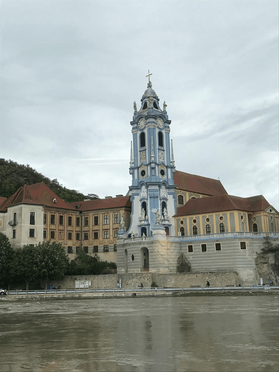 Beautiful view of a blue tower and nearby buildings from across a river on a cloudy day
