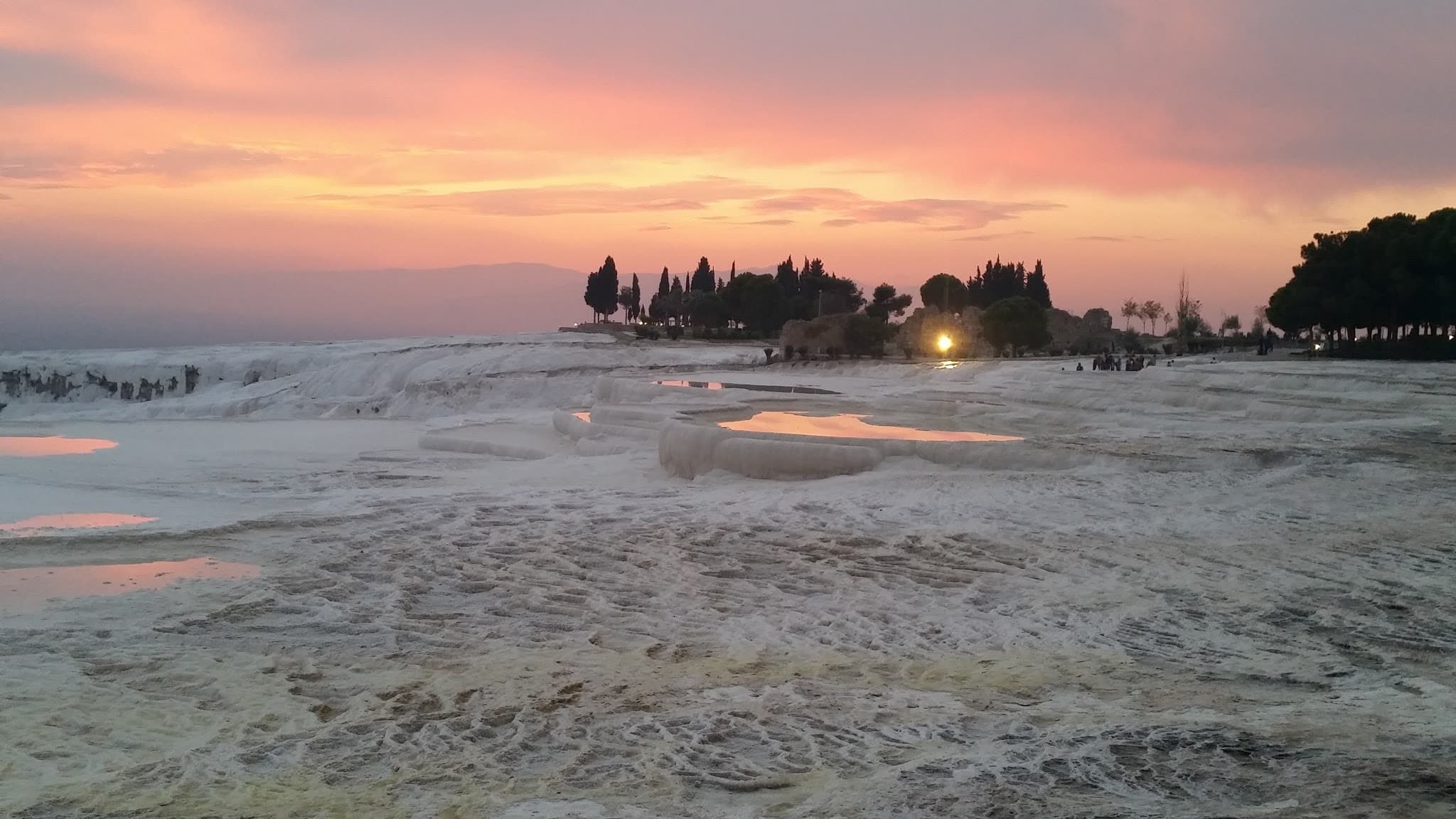 View of tide pools and small rapids under a pink and yellow sunset