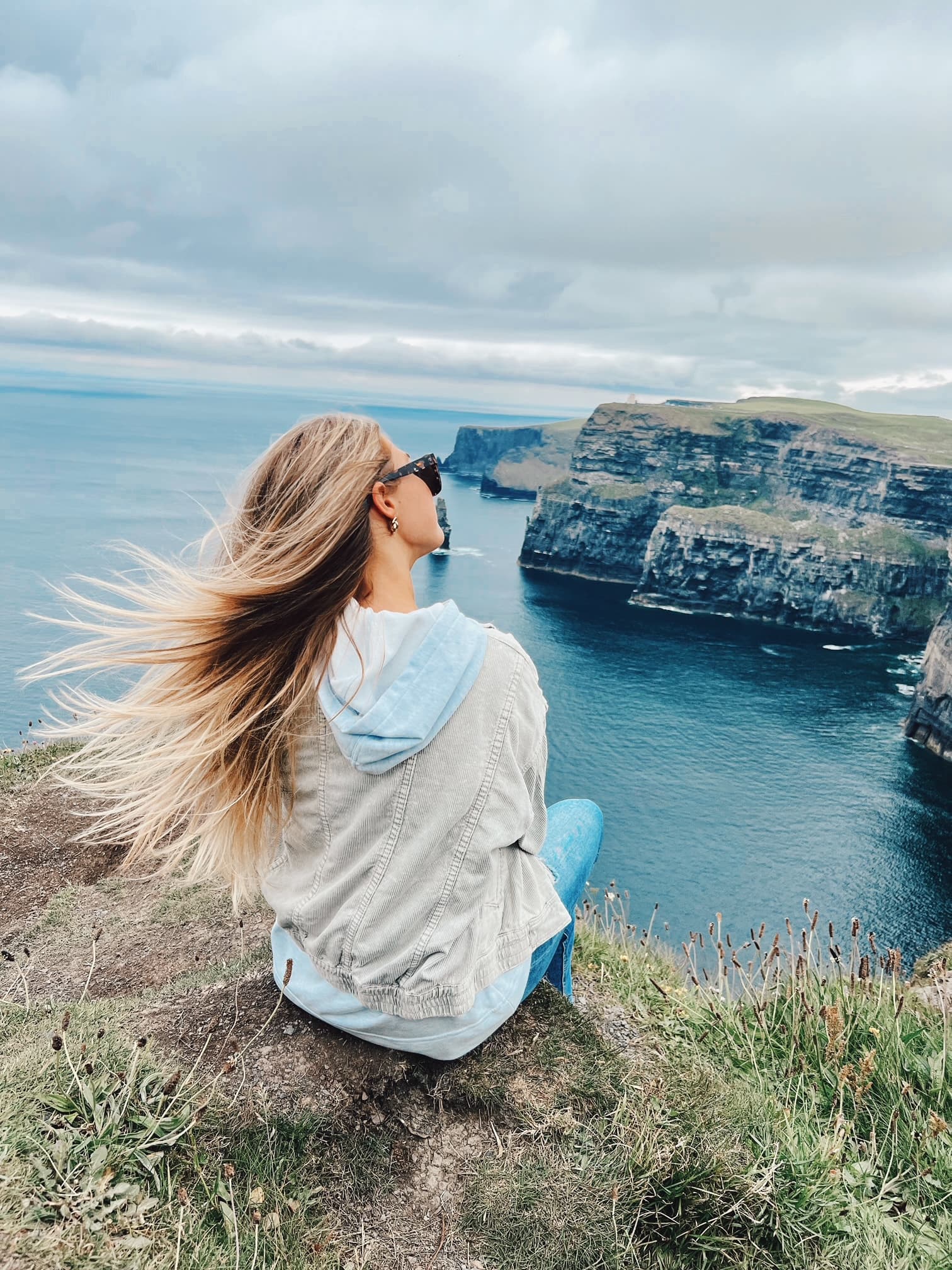 Advisor sitting on a cliff overlooking a coastal area on a cloudy day