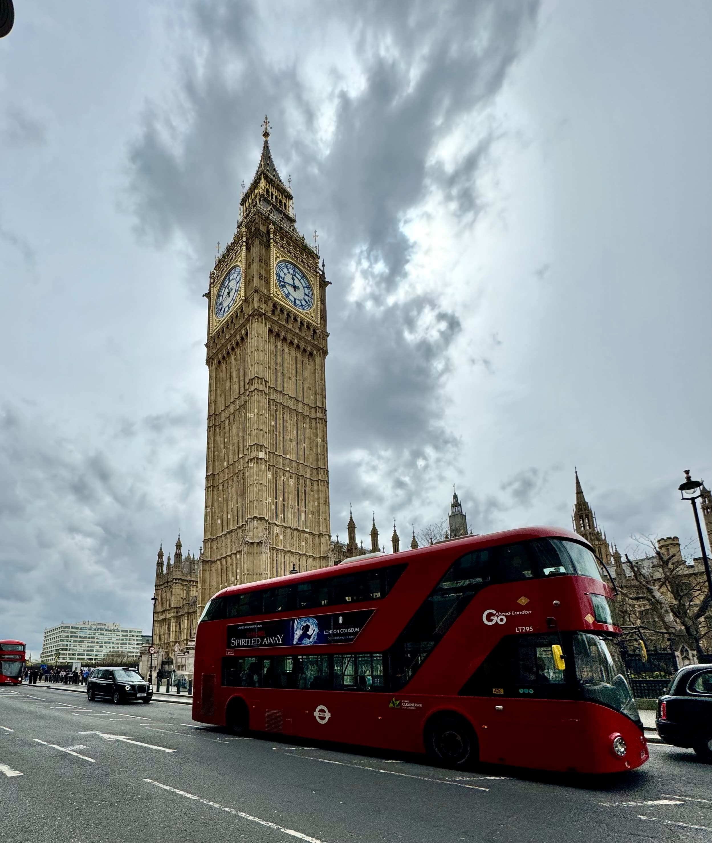 View of Big Ben and a red double decker bus on a cloudy day in London