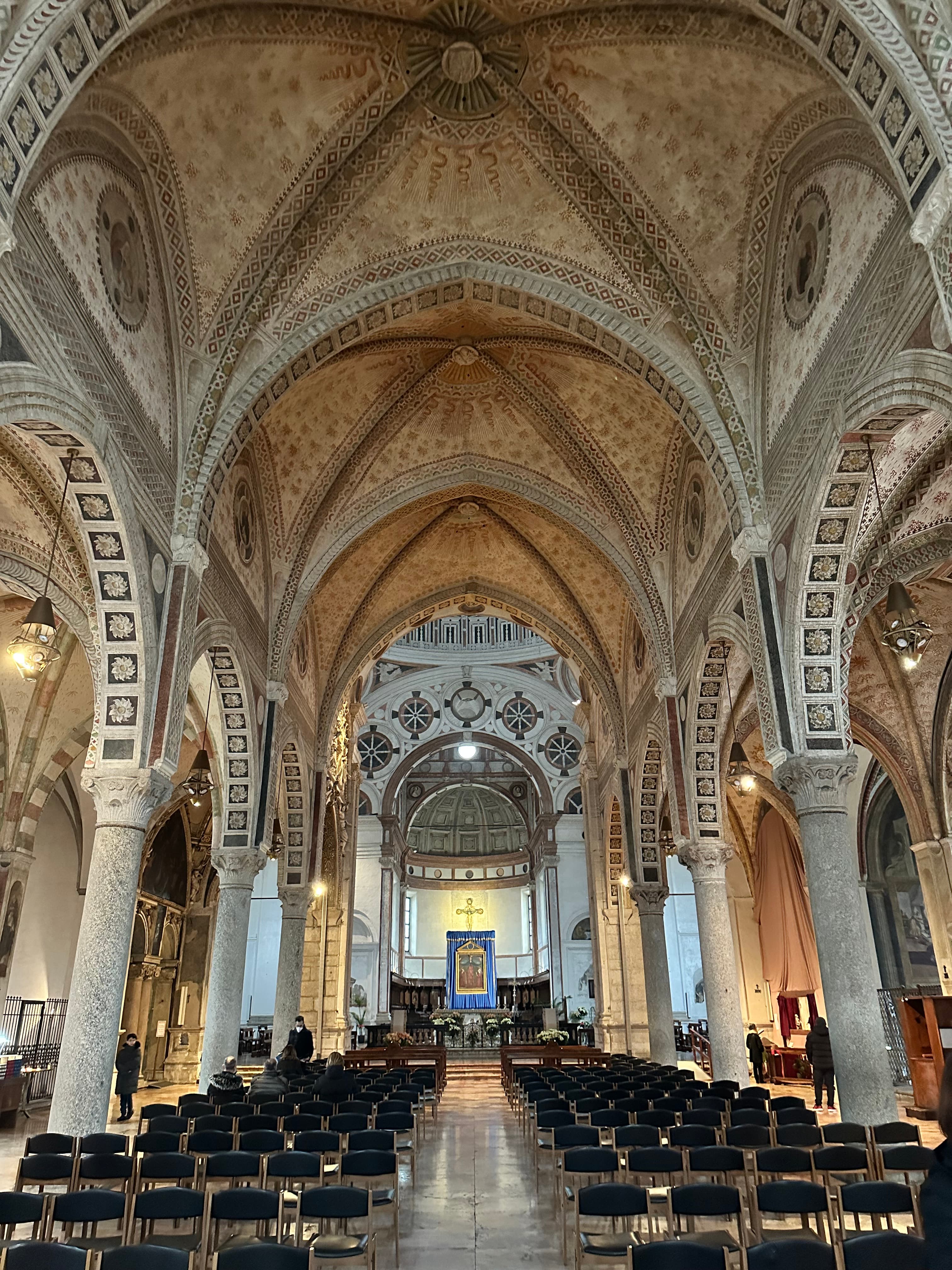 View of the center aisle and seats of a beautiful cathedral with rows of columns on either side