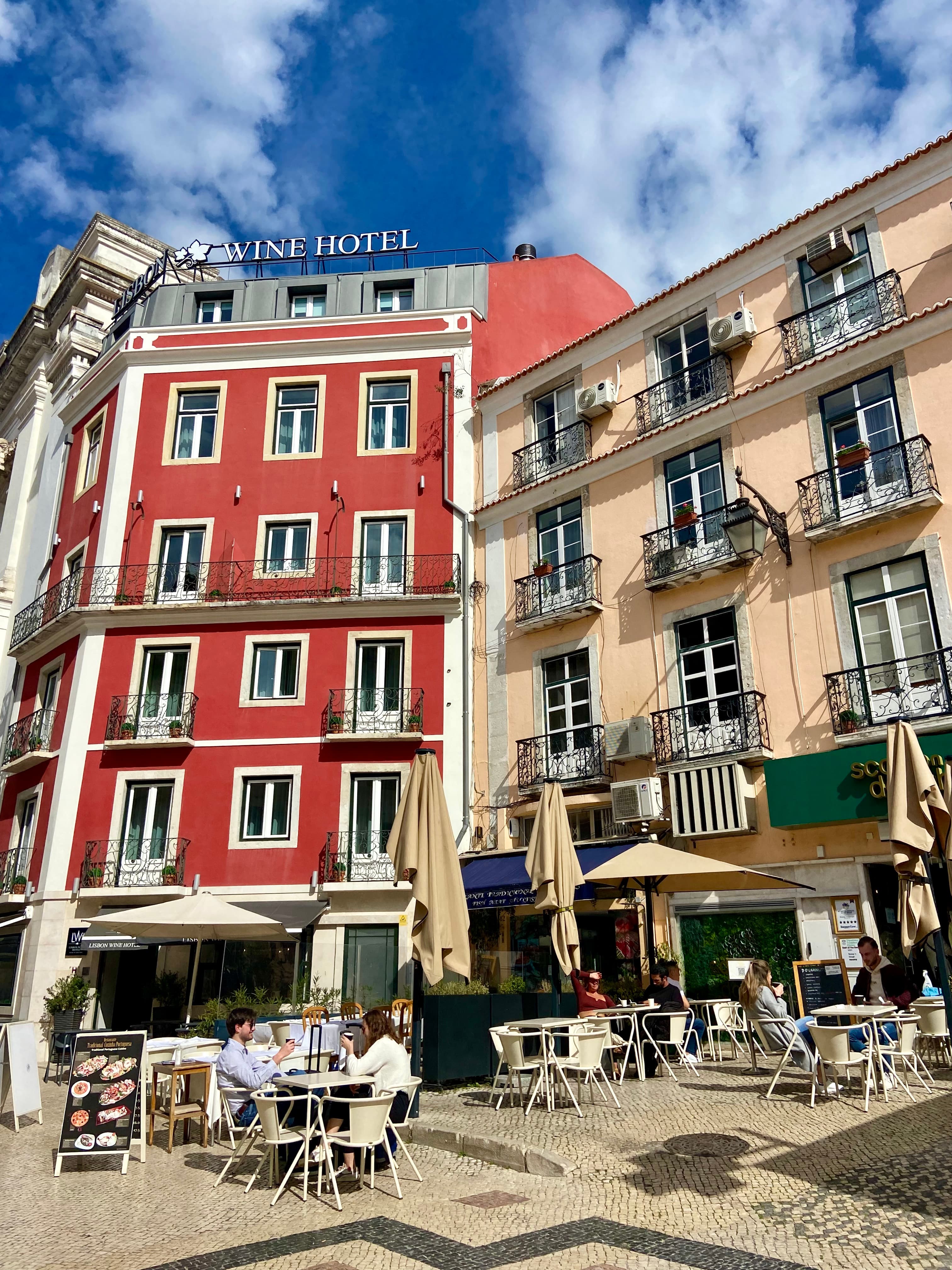 View of a charming city street corner with outdoor cafe seating on a sunny day