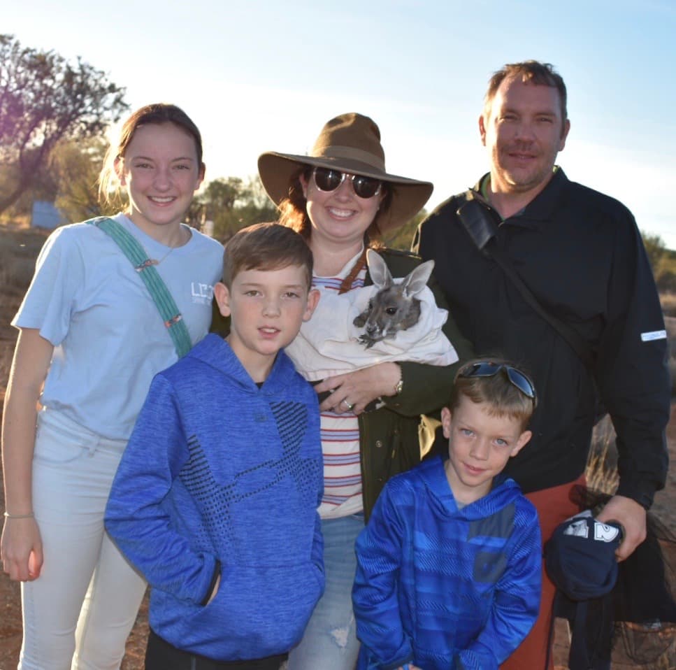 Advisor and her husband and three children posing together in a sunny environment