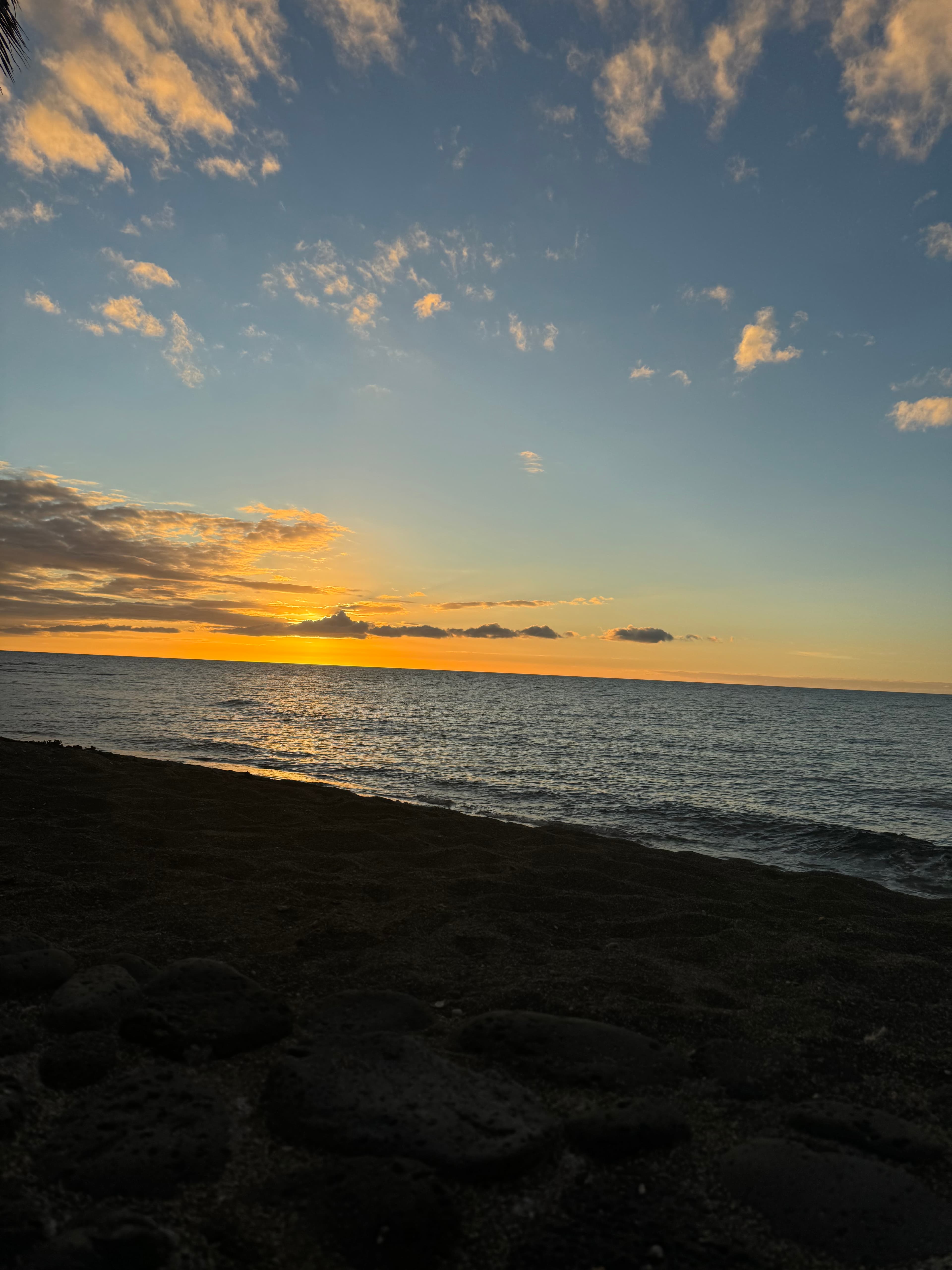 View of an orange and blue sunset on the horizon over a calm sea