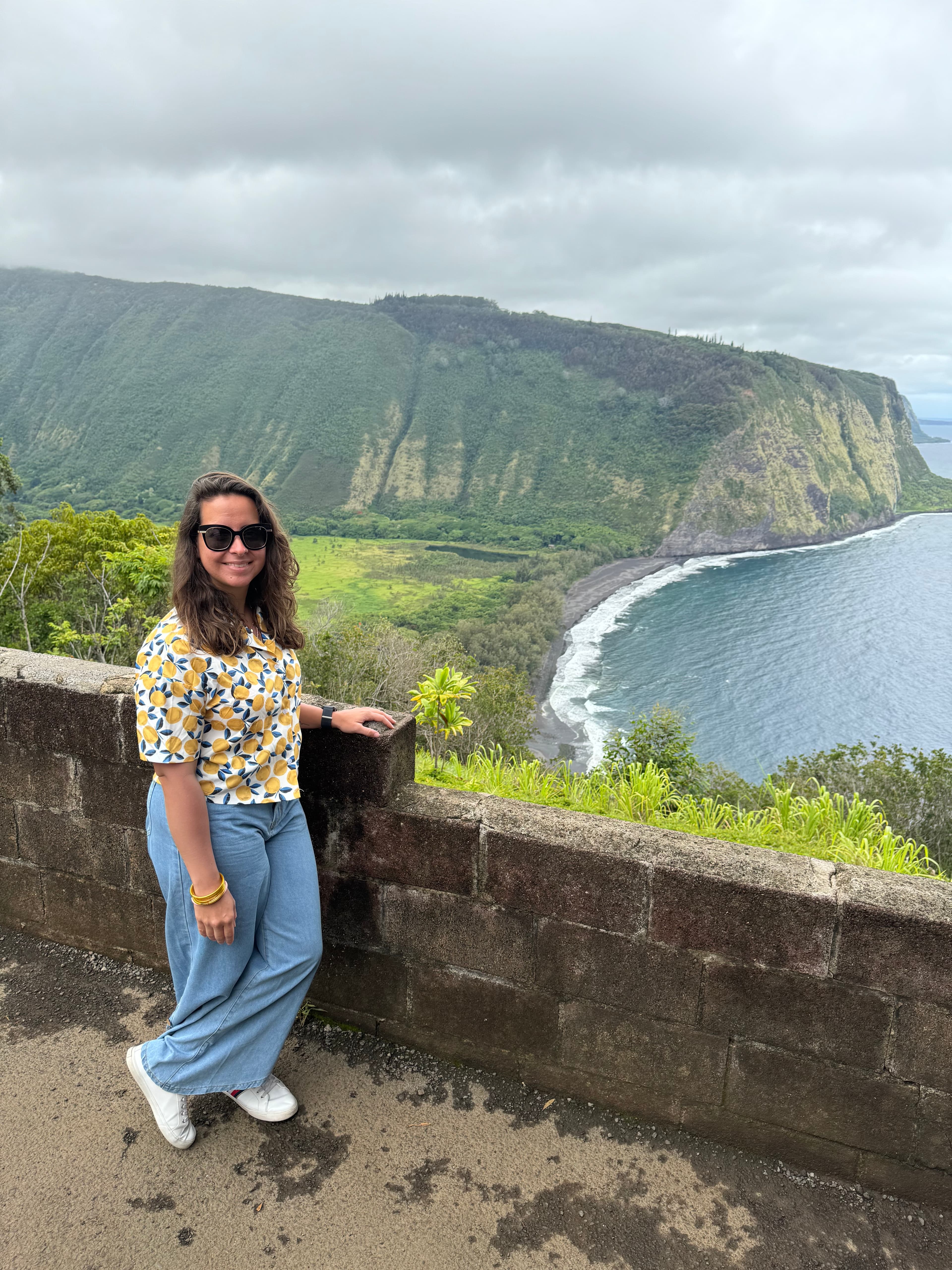 Sharon posing at a lookout point overlooking a beautiful coastal area with steep cliffs on a cloudy day
