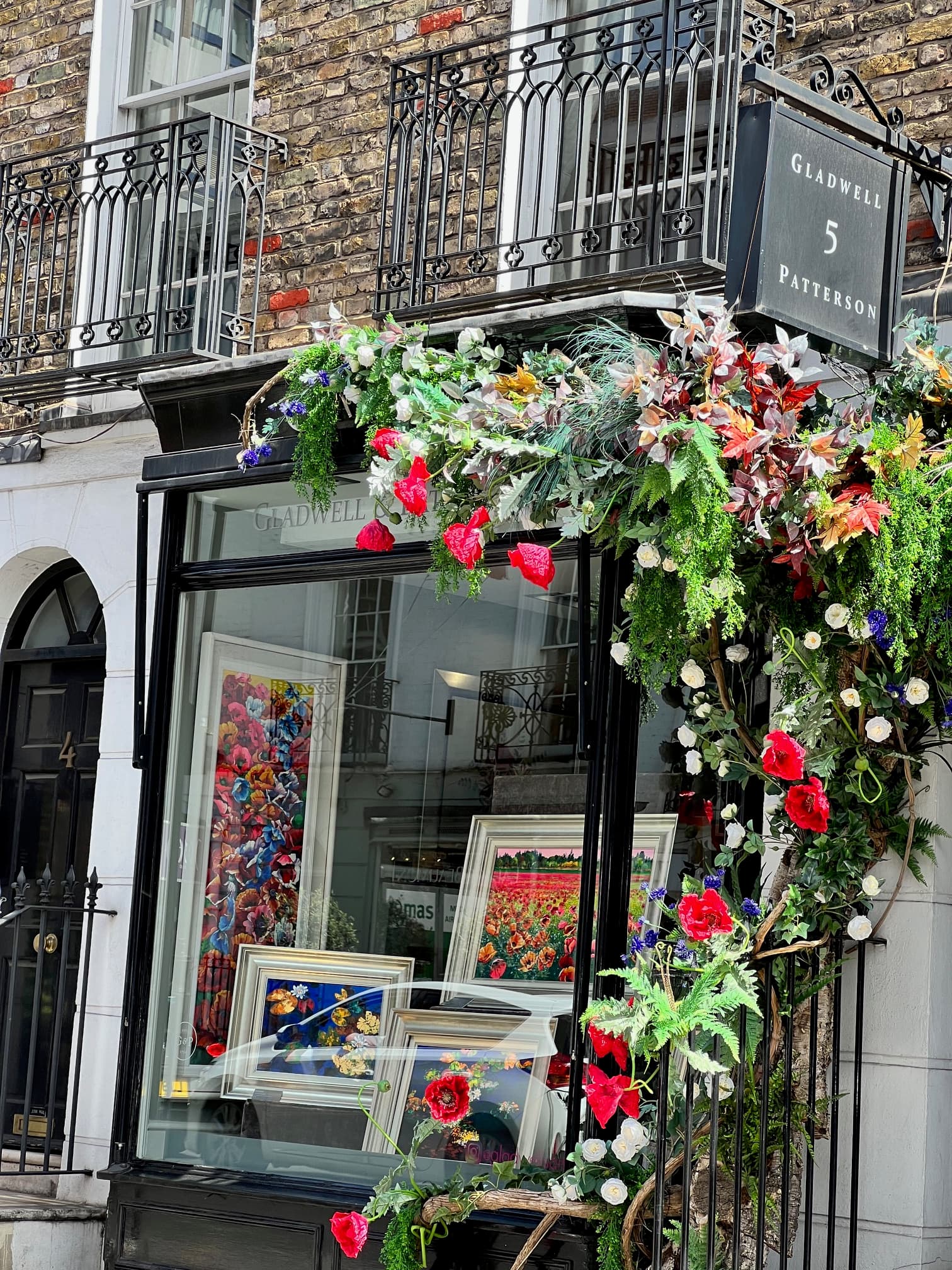 View of a glass window storefront on a street corner decorated with a beautiful flower display
