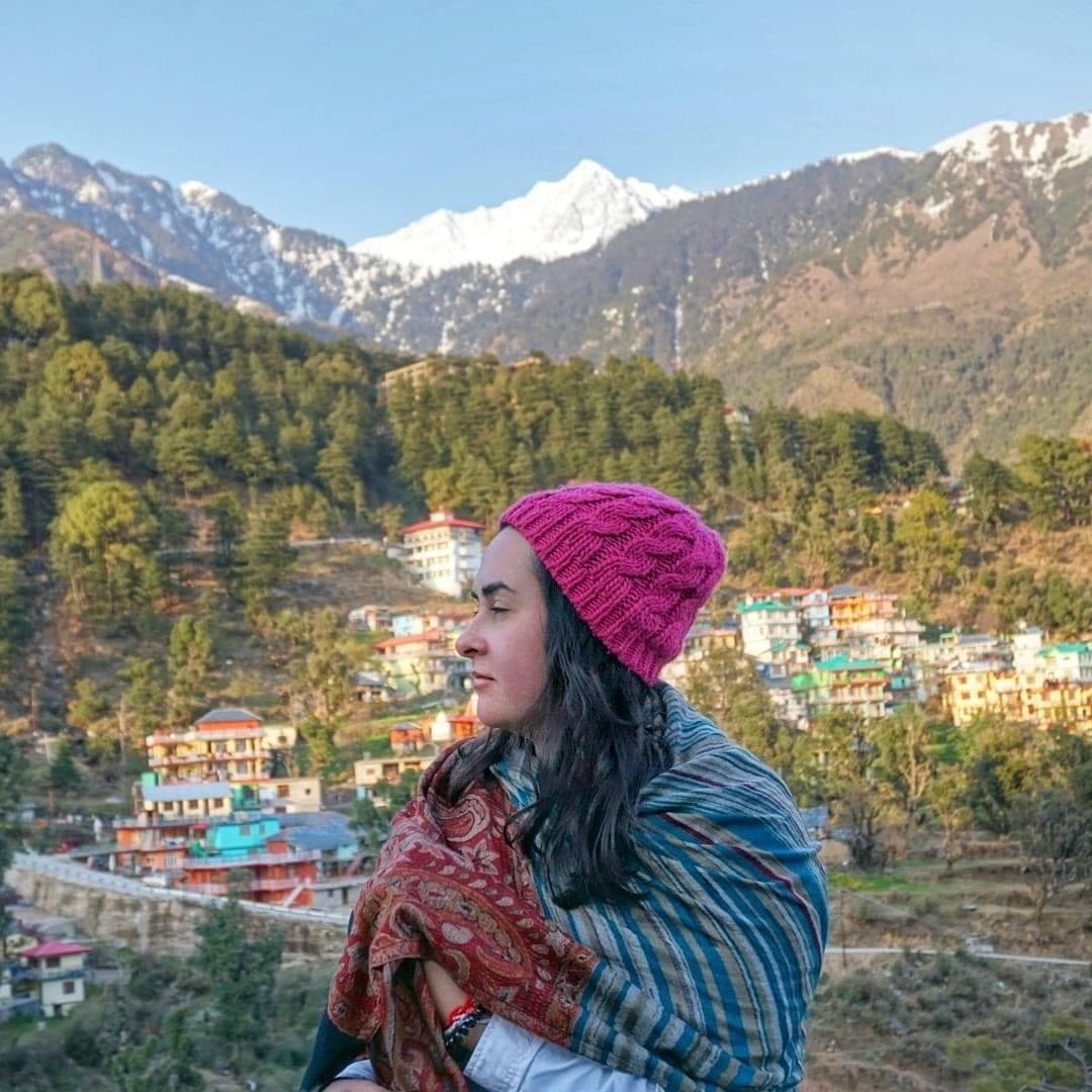 Advisor in a pink knit hat in front of a stunning mountain backdrop on a sunny day