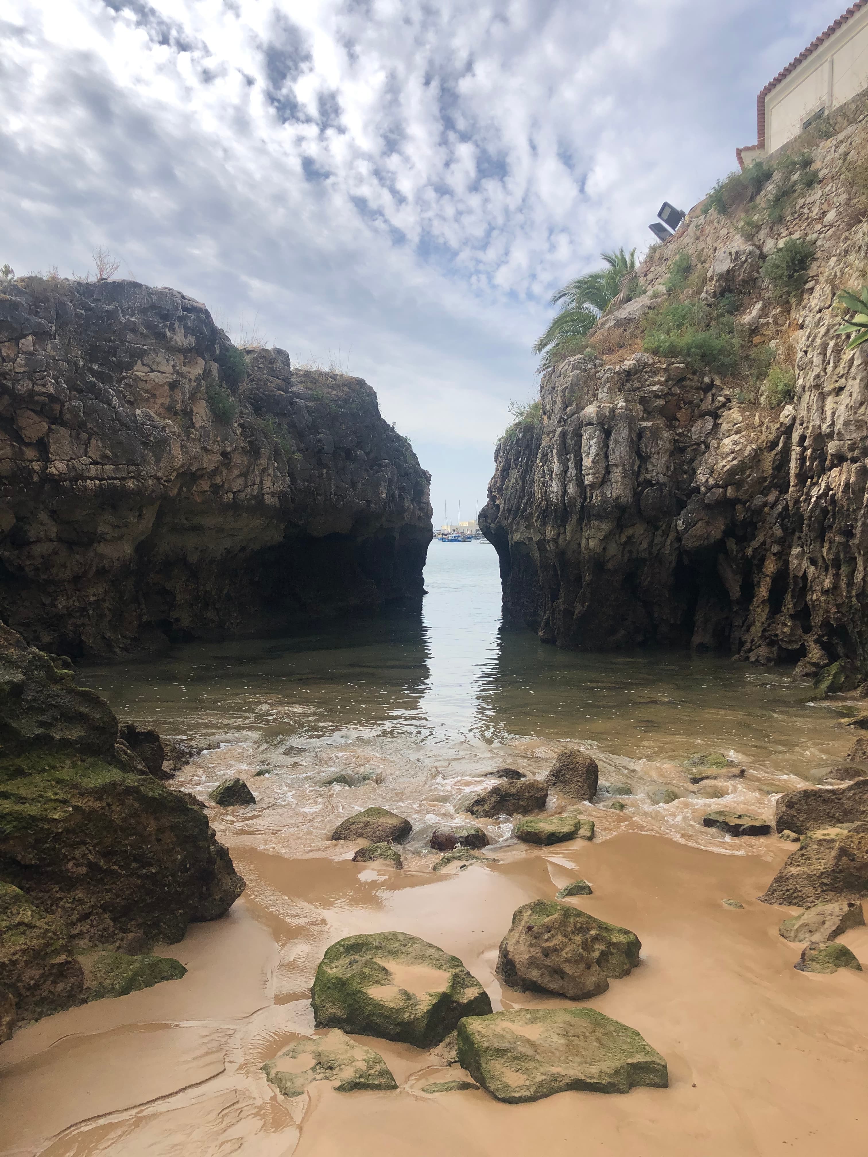 View of the ocean seen from the beach between a crevice in two rock formations