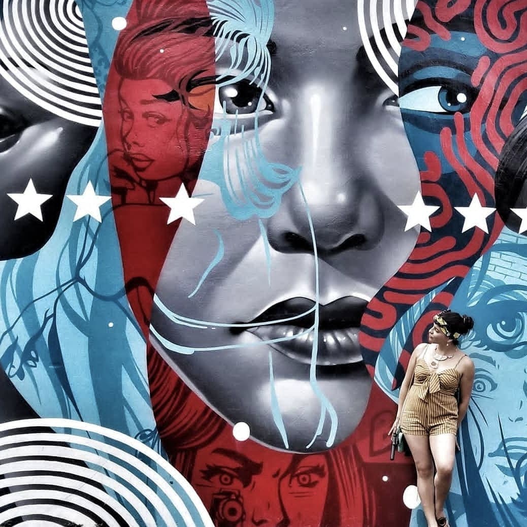 Advisor posing in front of a mural of a face decorated with red white and blue patterns
