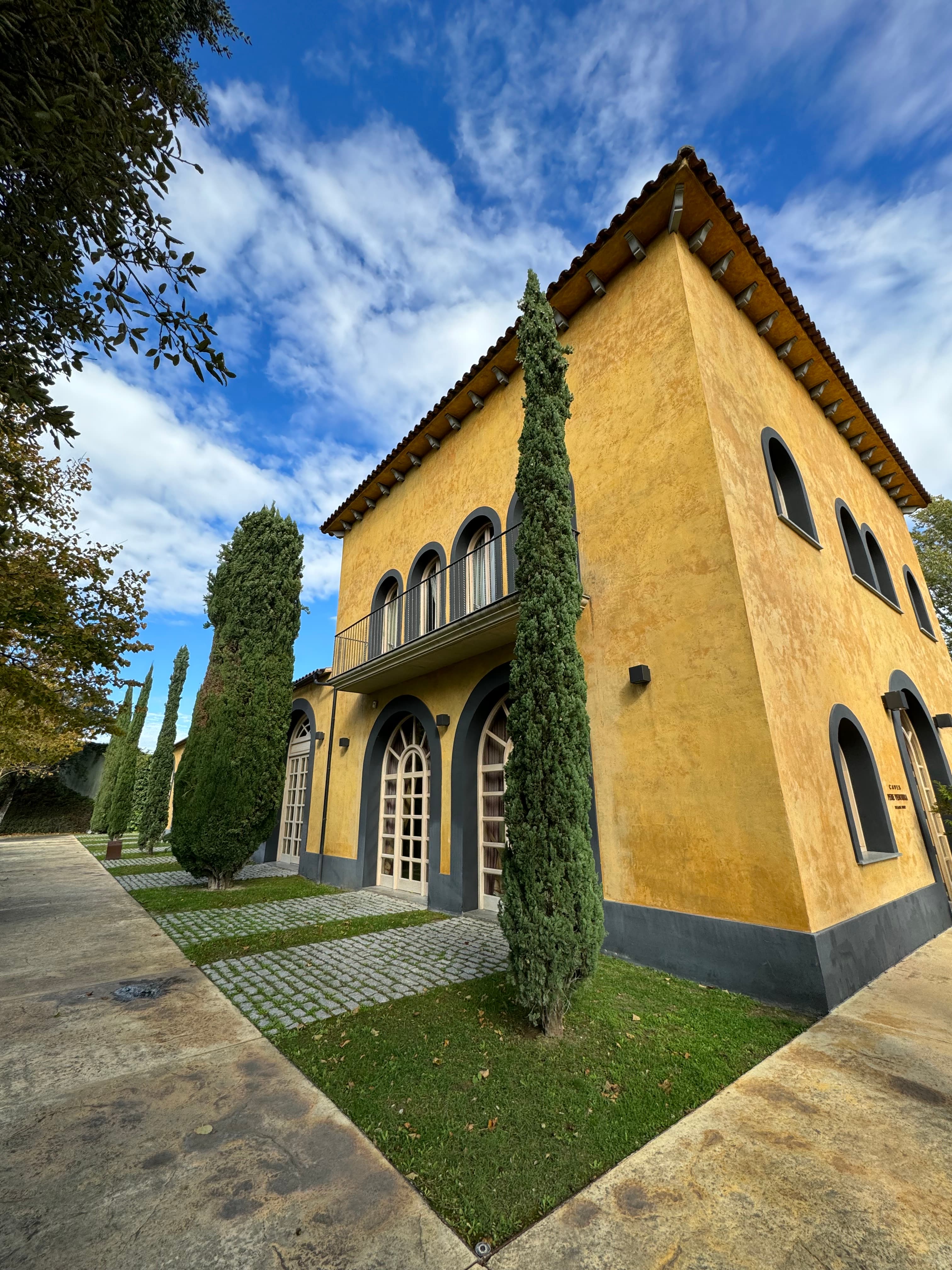 A view of a yellow building on a sunny day with foliage in the distance.