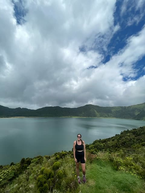 Advisor posing with a view of a lake and foliage in the distance on a cloudy day.