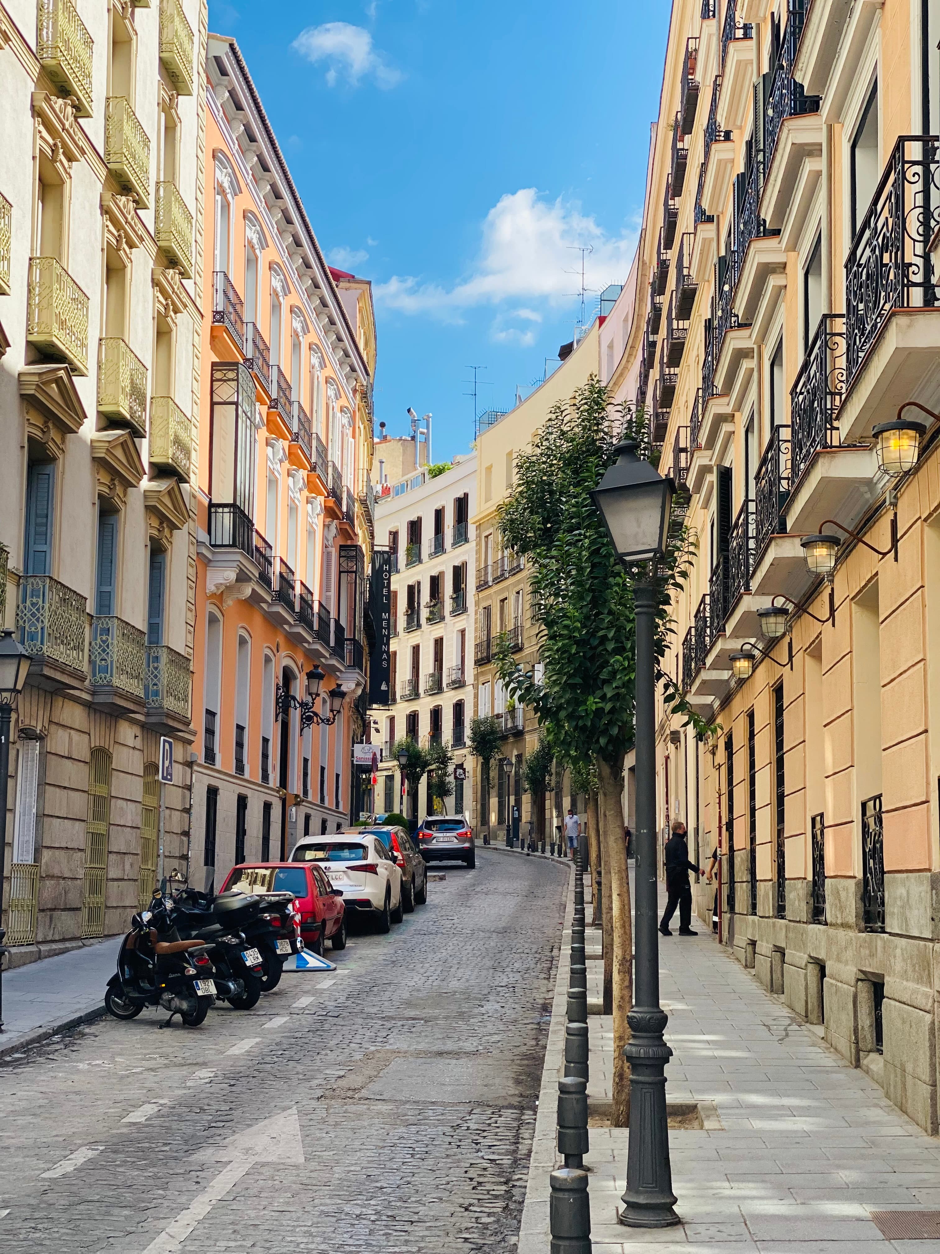 Historic buildings line a quiet street as the sun sets under a clear sky. 