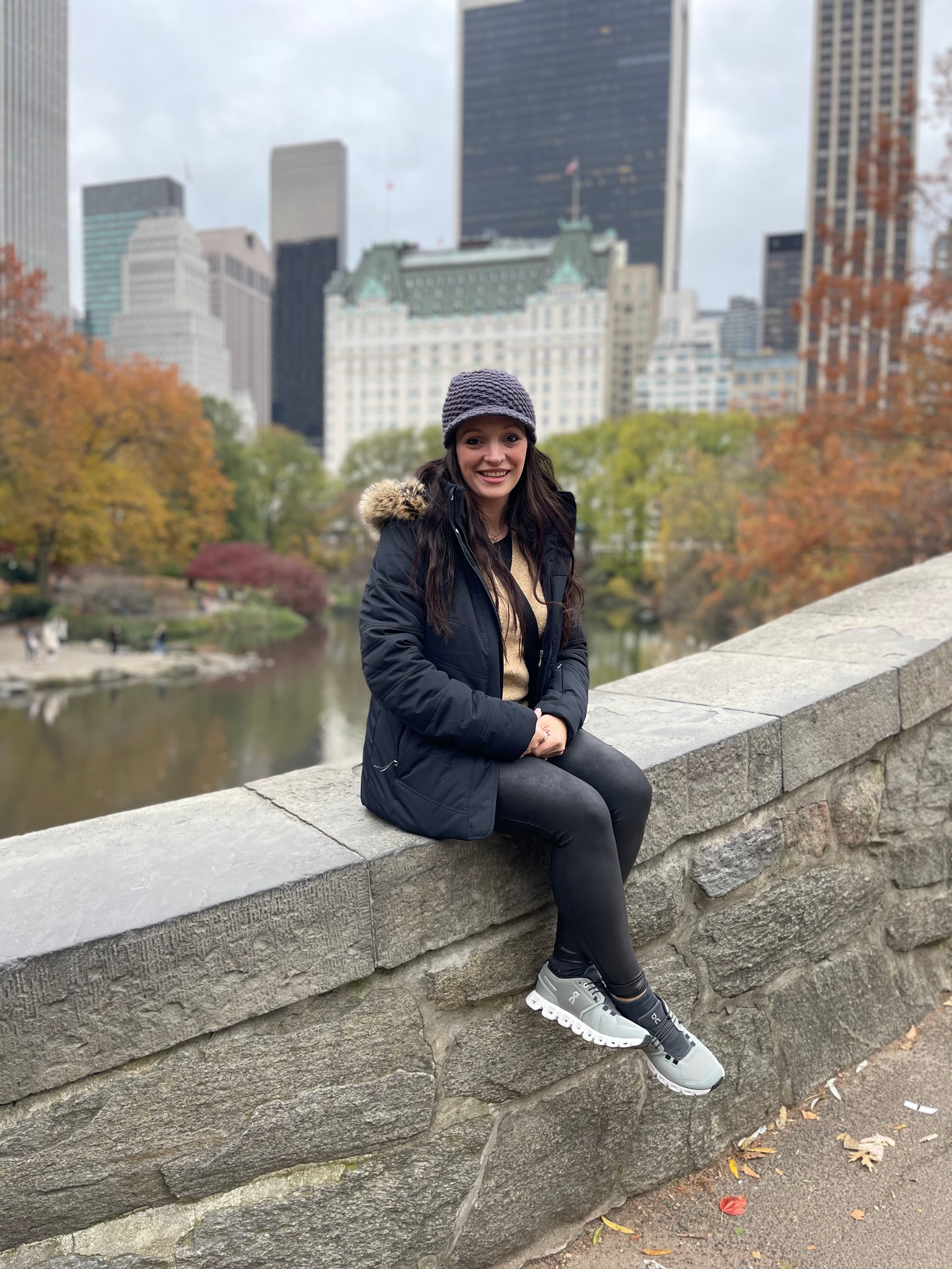 Advisor wearing a winter jacket sitting on a bridge in Central Park on a cloudy day