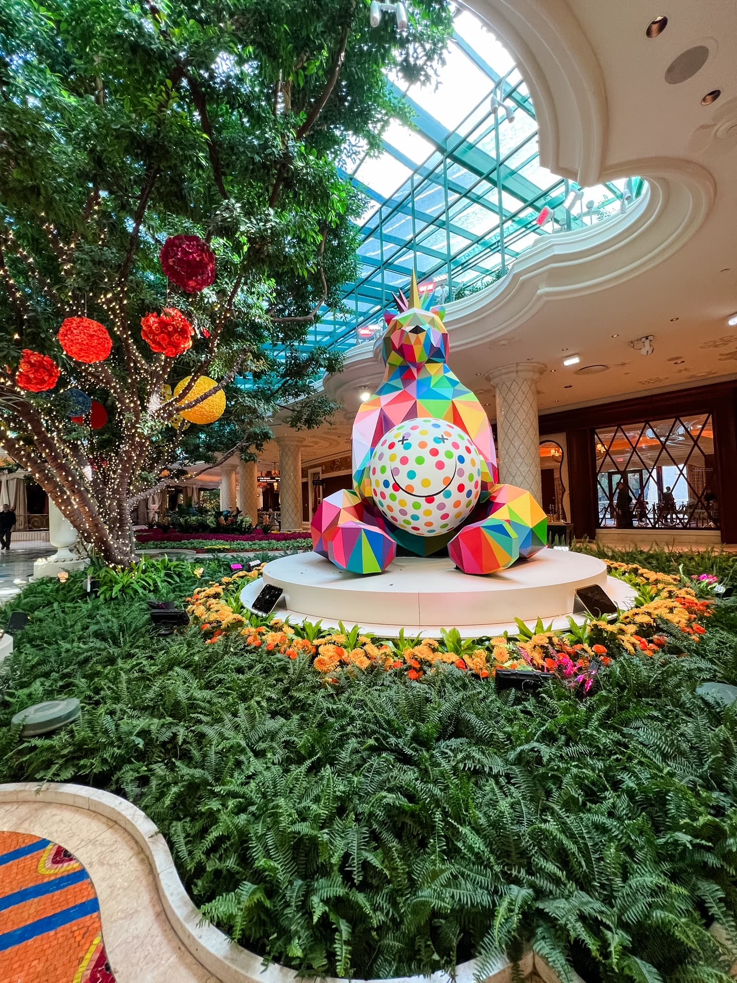 View of a colorful sculpture set amidst plants indoors at a shopping mall