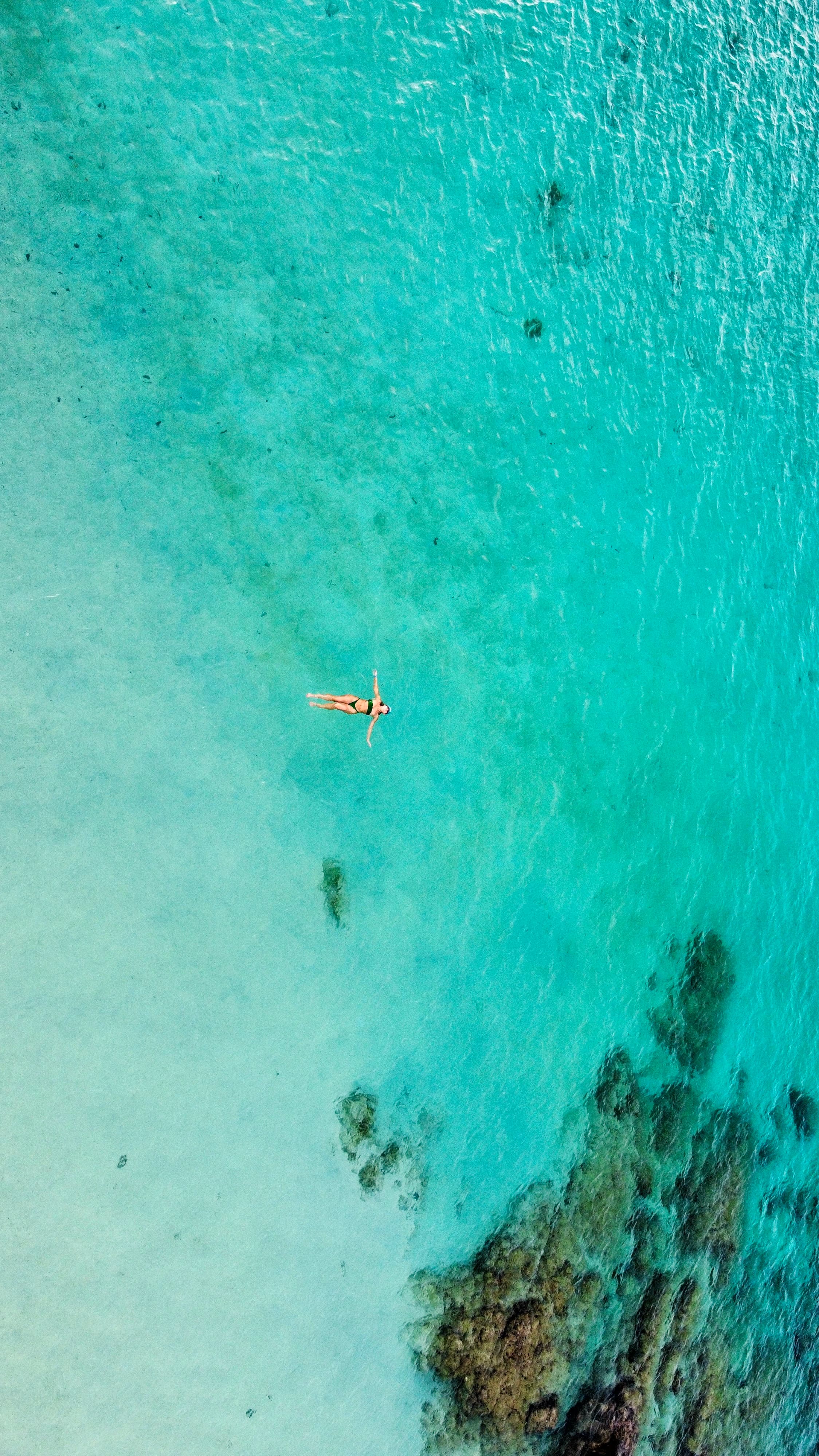 Overhead view of a clear turquoise sea with a coral formation